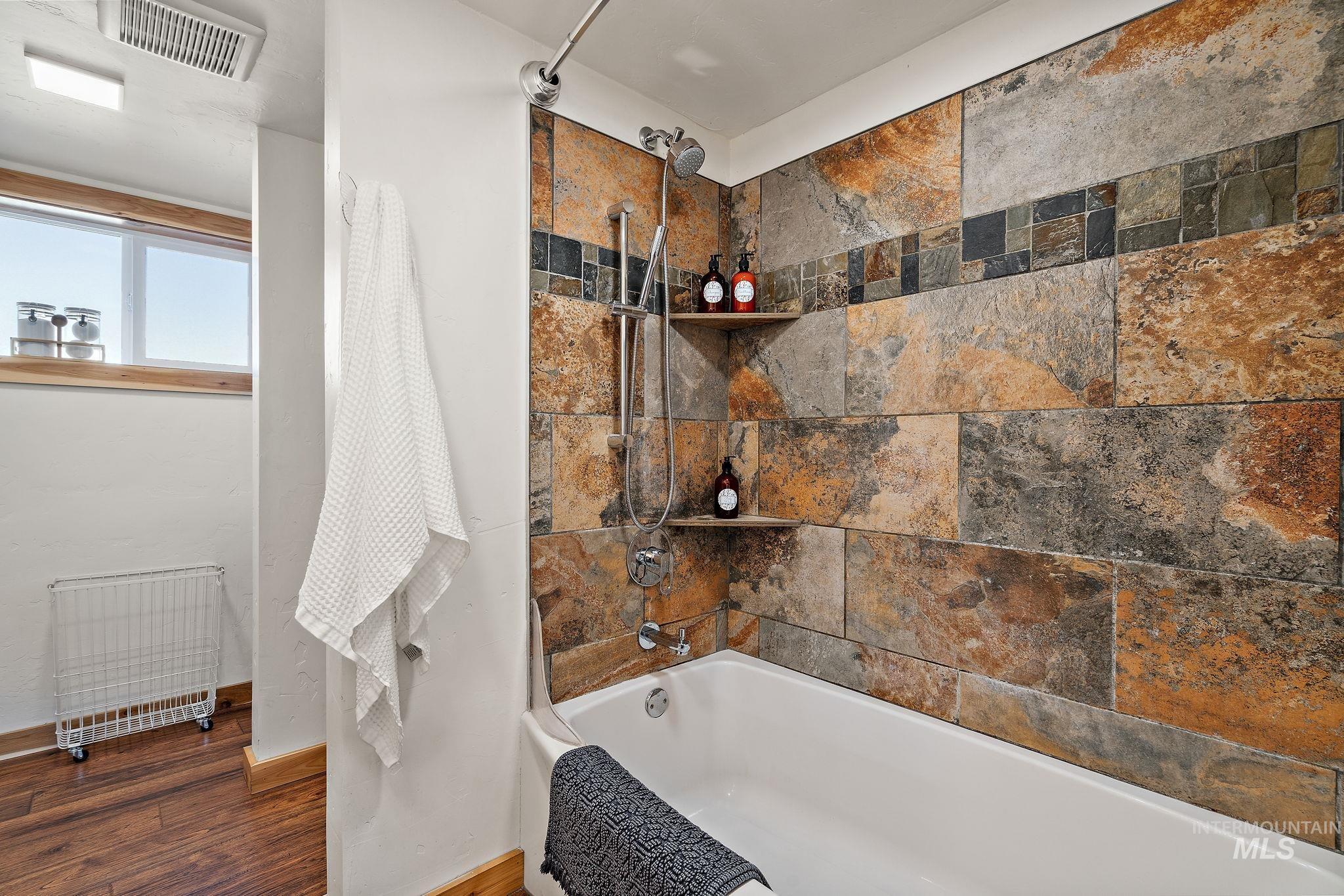 Full bathroom with shower / bathtub combination, wood finished floors, and radiator heating unit