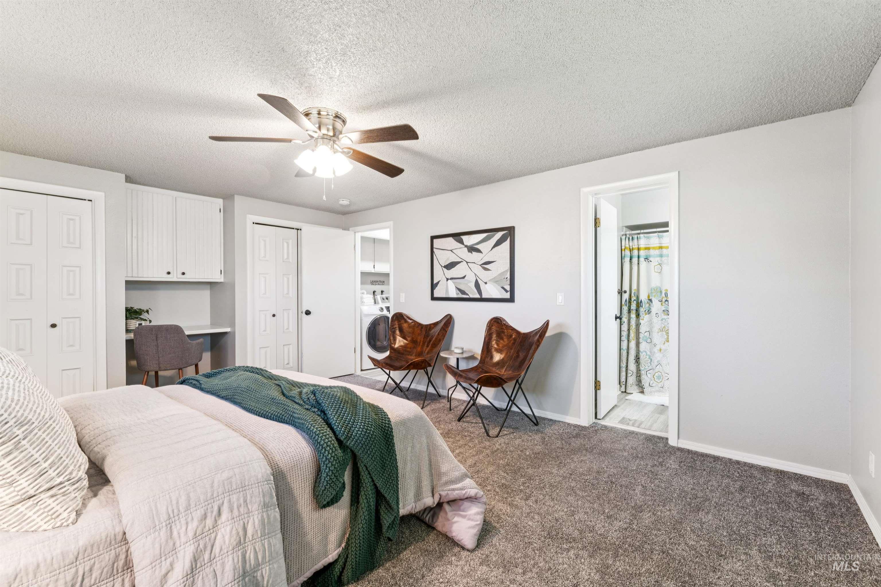 Bedroom featuring carpet flooring, two closets, connected bathroom, a textured ceiling, and a ceiling fan