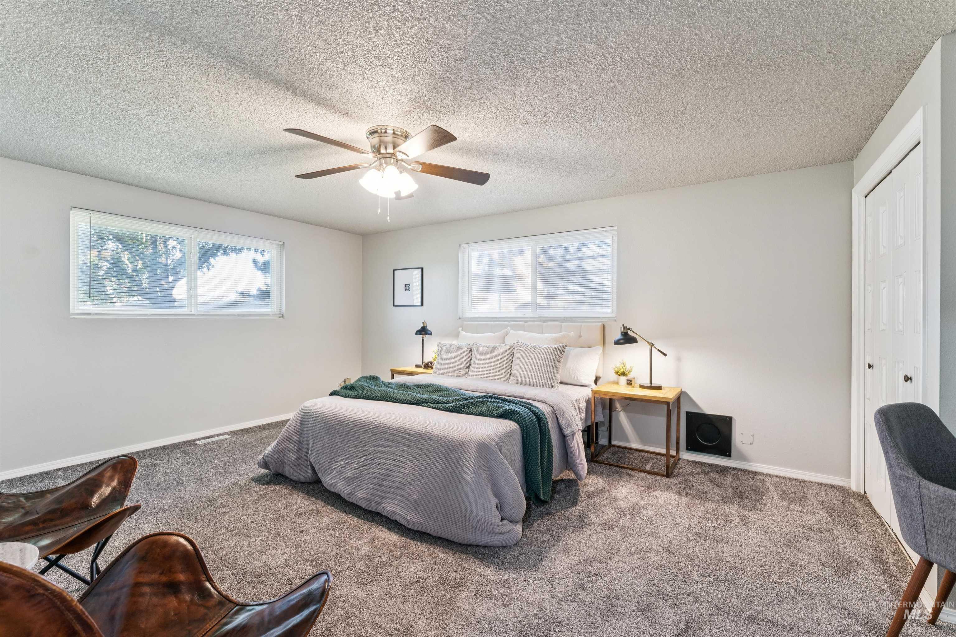 Bedroom with carpet, multiple windows, a closet, ceiling fan, and a textured ceiling