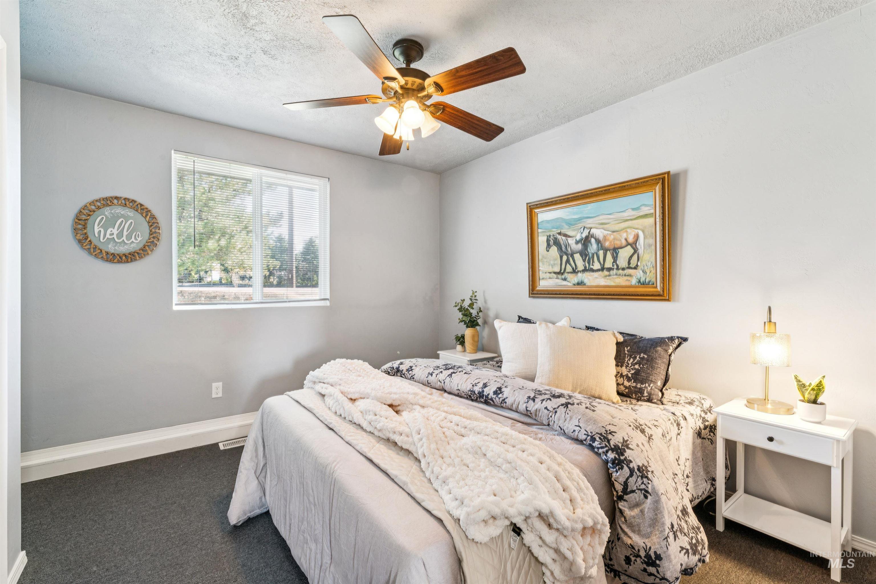 Carpeted bedroom with a textured ceiling and ceiling fan