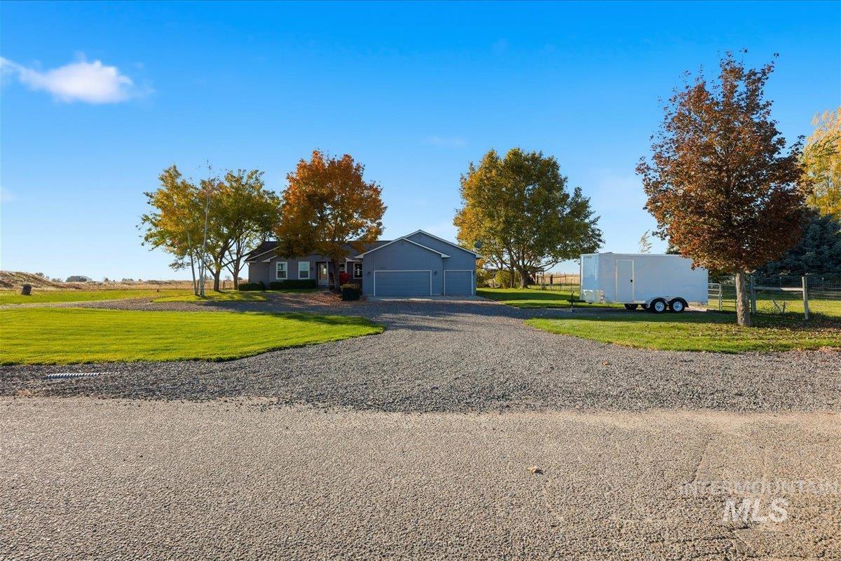View of front of home with a front lawn, gravel driveway, and a garage