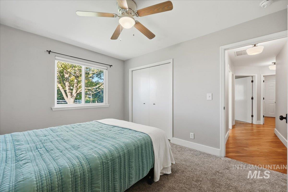 Bedroom with light carpet, ceiling fan, and a closet