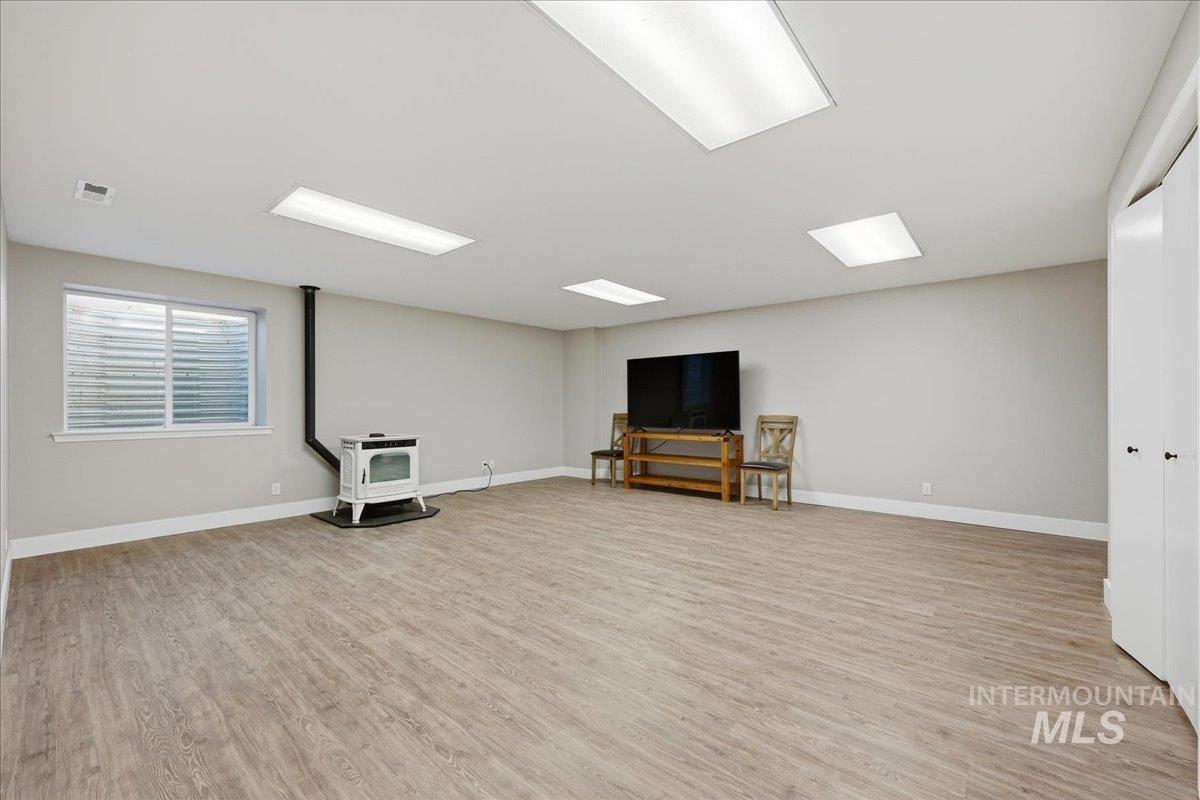Basement with a wood stove and light wood-style flooring