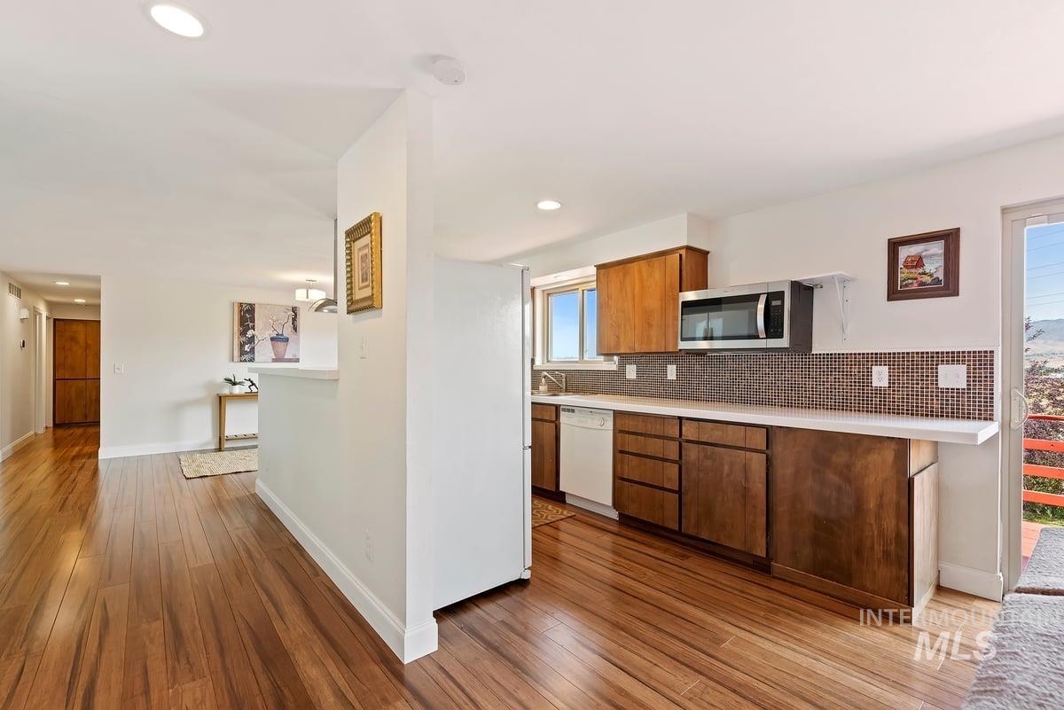 Kitchen with stainless steel microwave, white dishwasher, light countertops, hardwood / wood-style floors, and recessed lighting
