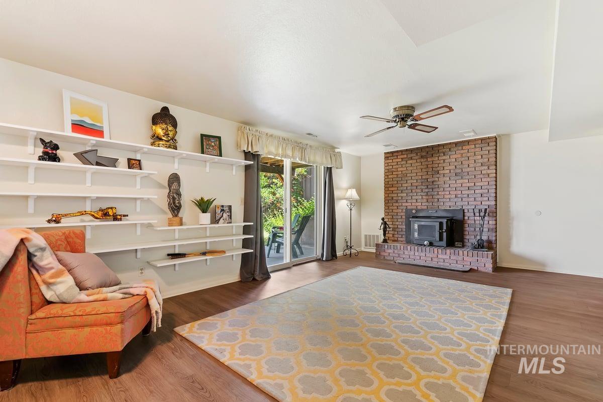 Living room featuring wood finished floors, a ceiling fan, and a wood stove