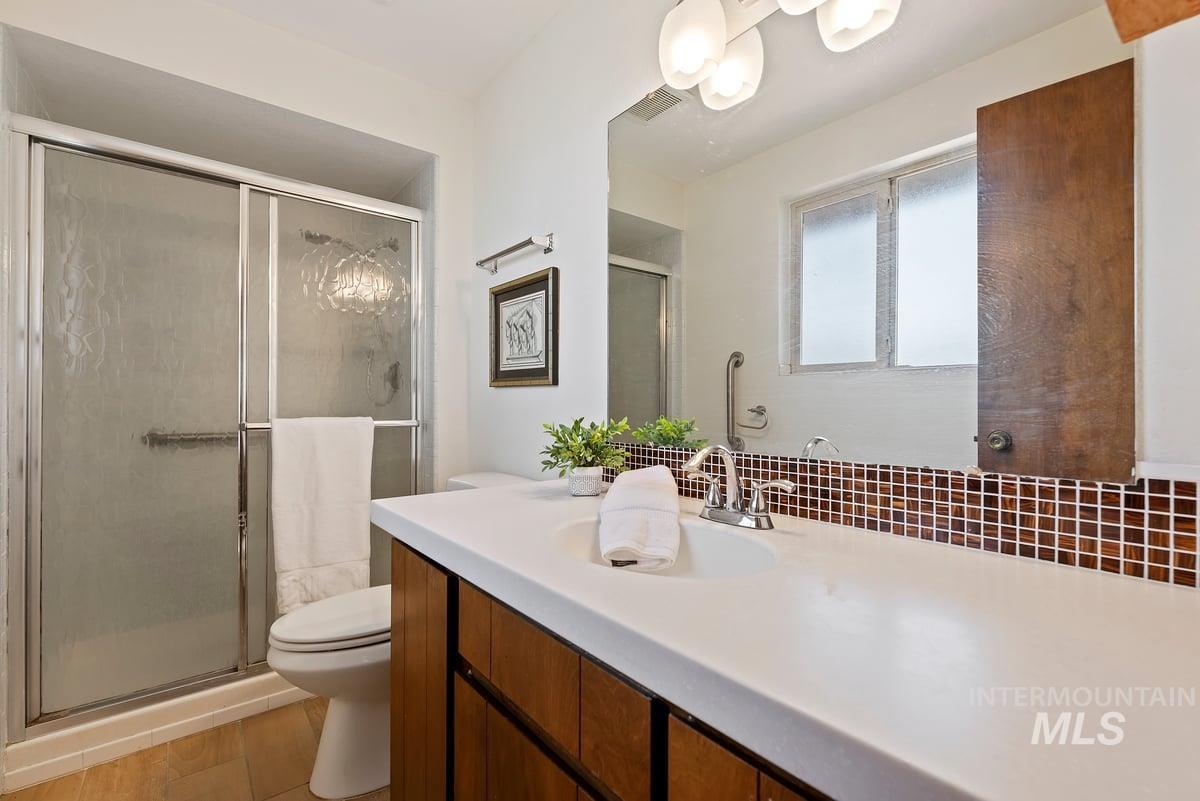 Full bath with vanity, a stall shower, and wood finished floors