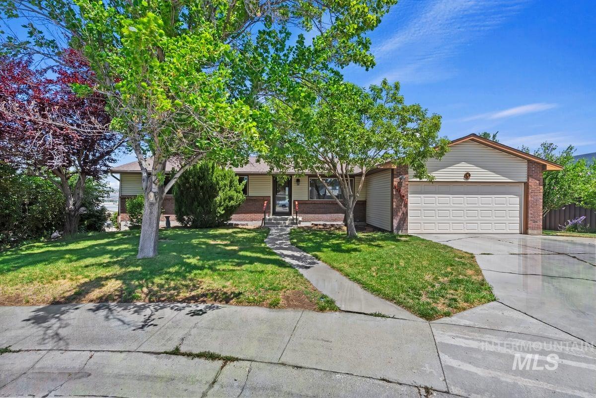 View of front of house with brick siding, a garage, a front lawn, driveway, and a porch