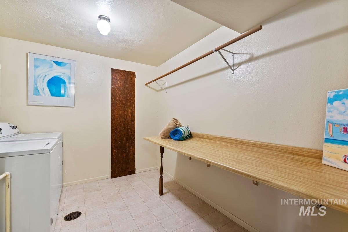 Laundry room with light tile patterned floors and washing machine and clothes dryer