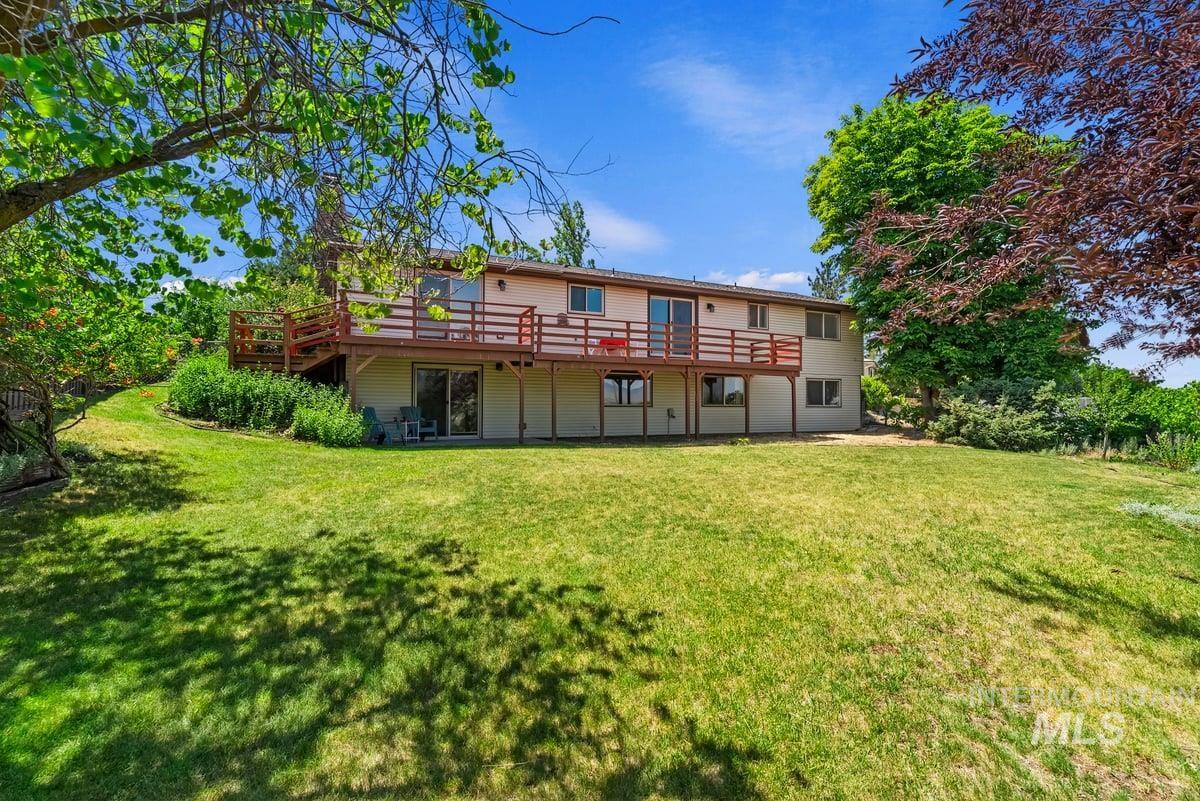 Back of house with a wooden deck and a yard