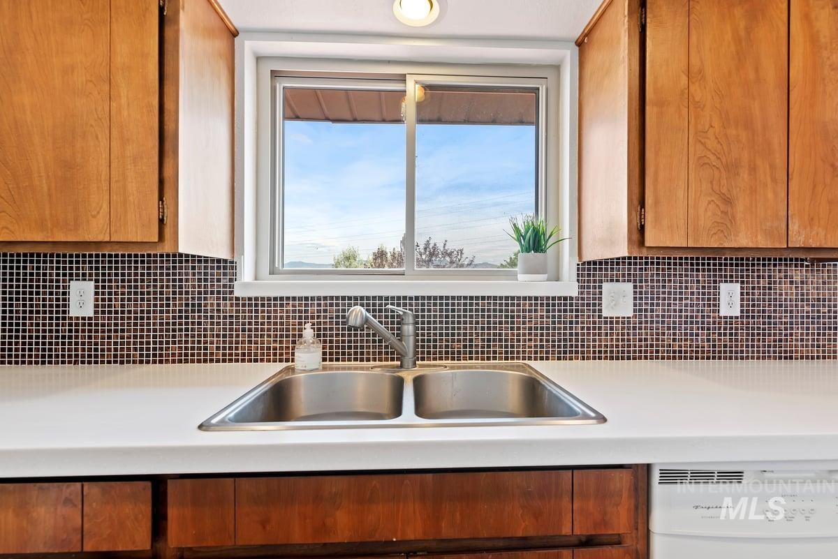 Kitchen featuring dishwasher, decorative backsplash, and brown cabinetry