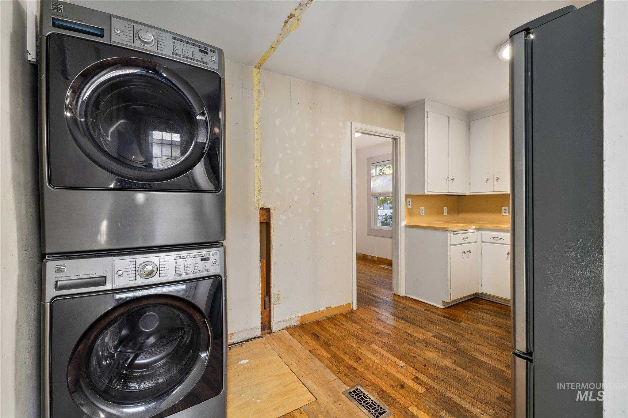 Laundry room with dark wood-style floors and estacked washer and dryer