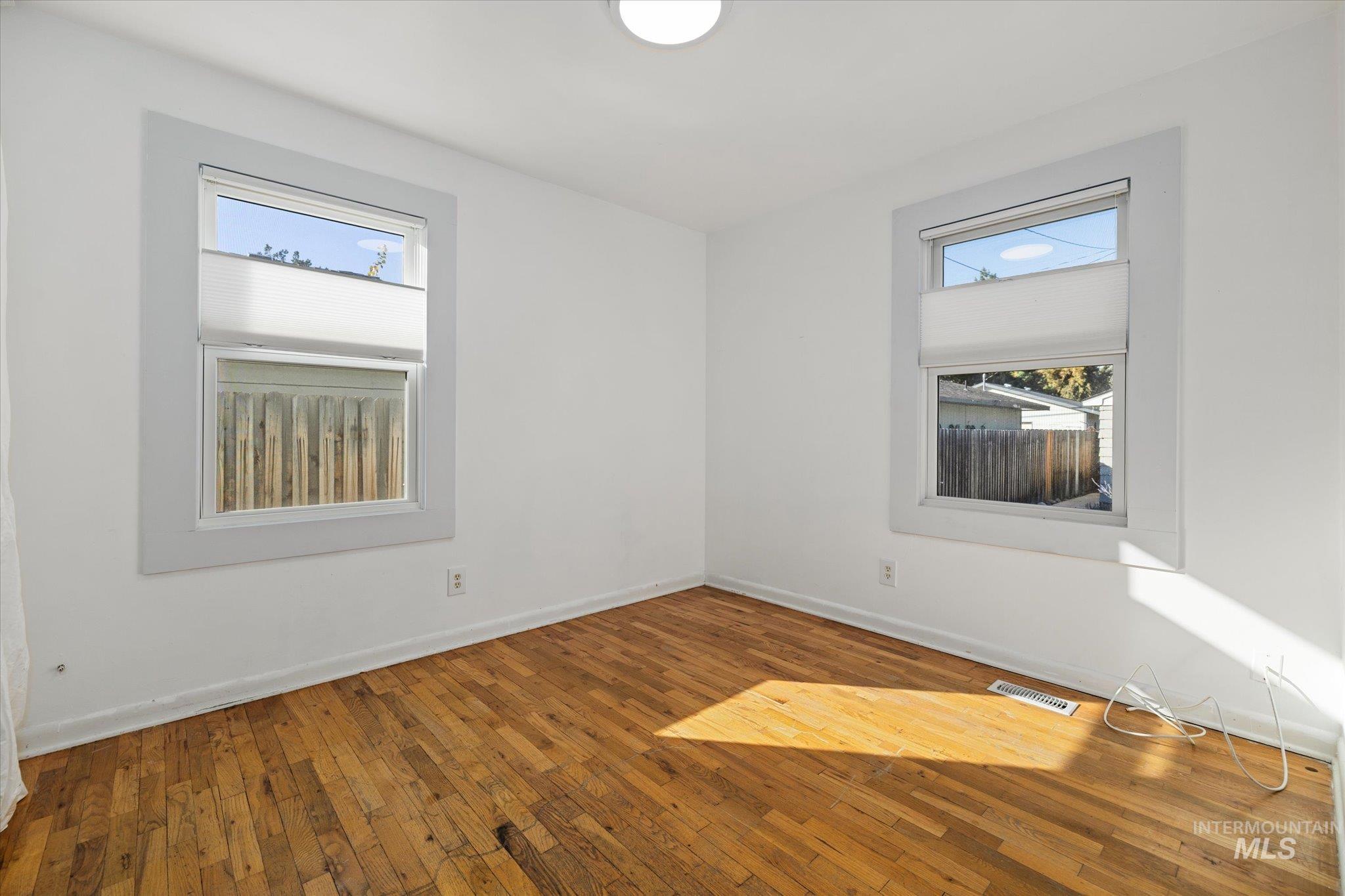 Empty room with hardwood / wood-style floors and baseboards