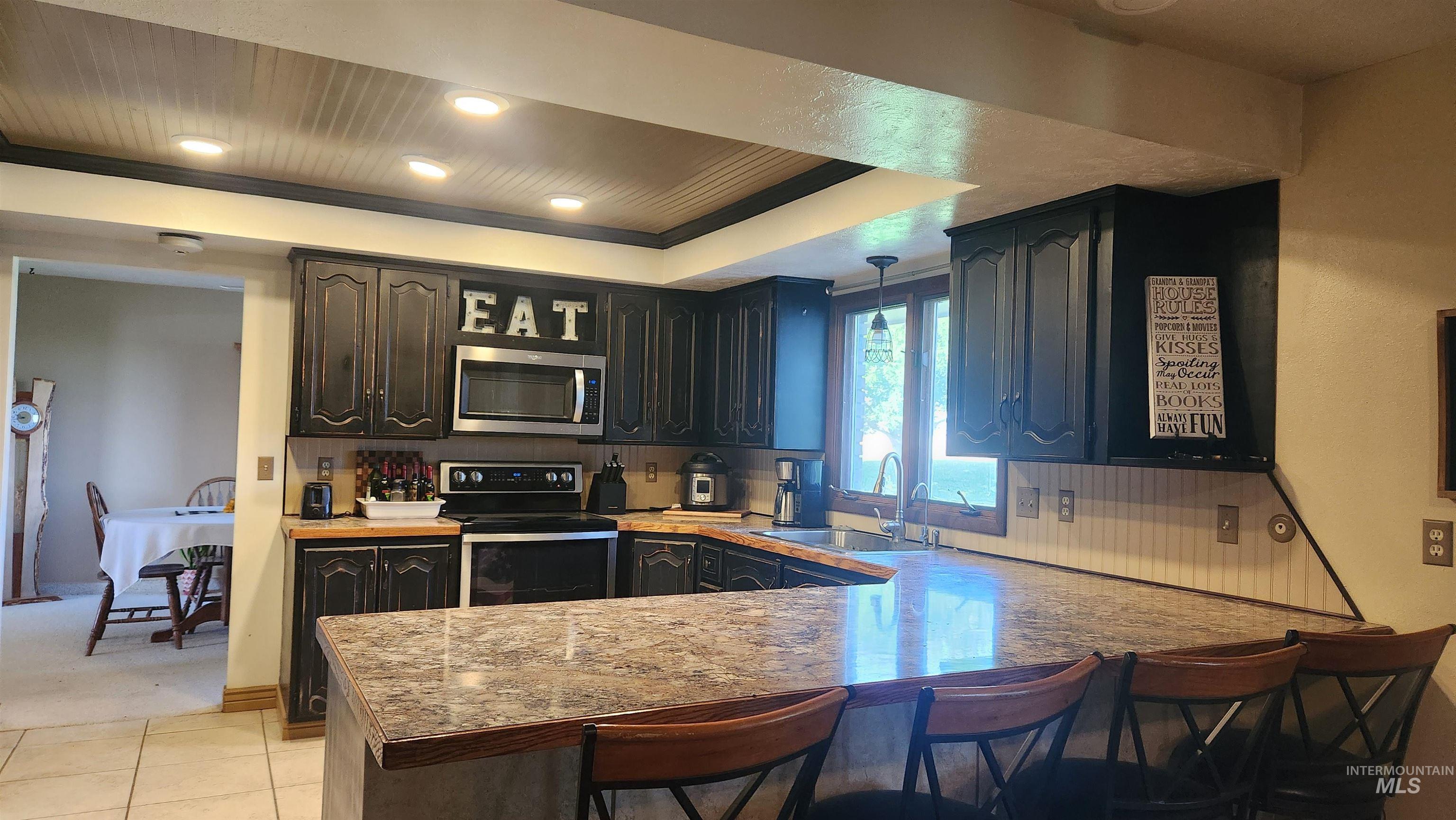 Kitchen with a kitchen breakfast bar, electric range, pendant lighting, a peninsula, and stainless steel microwave