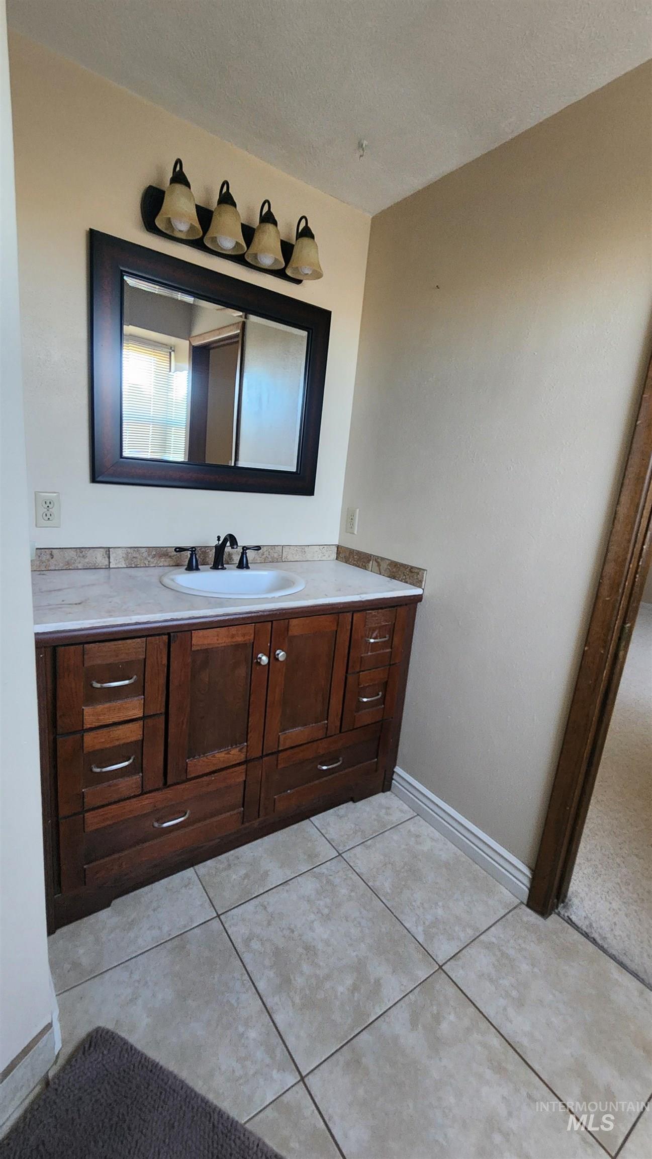 Bathroom featuring vanity, a textured ceiling, and light tile patterned flooring