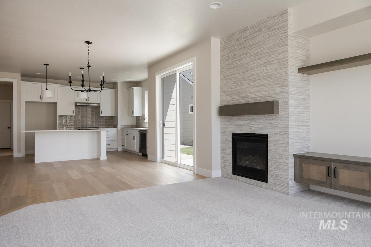 Unfurnished living room with light colored carpet, light wood-style floors, a large fireplace, and recessed lighting