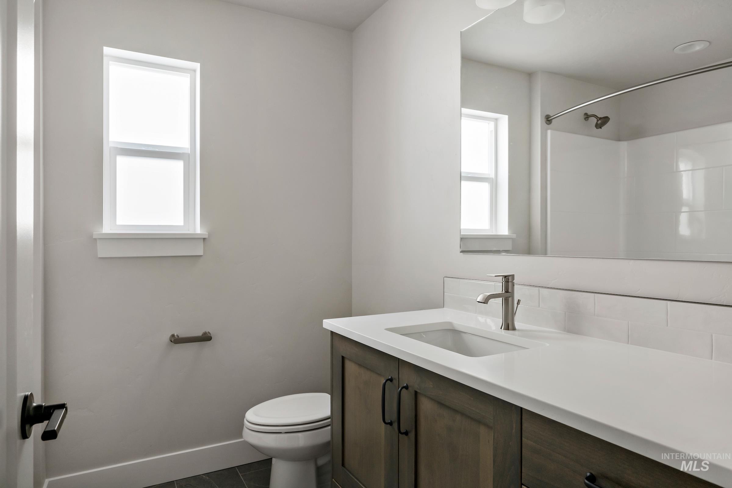 Full bath with vanity, dark tile patterned floors, and a shower