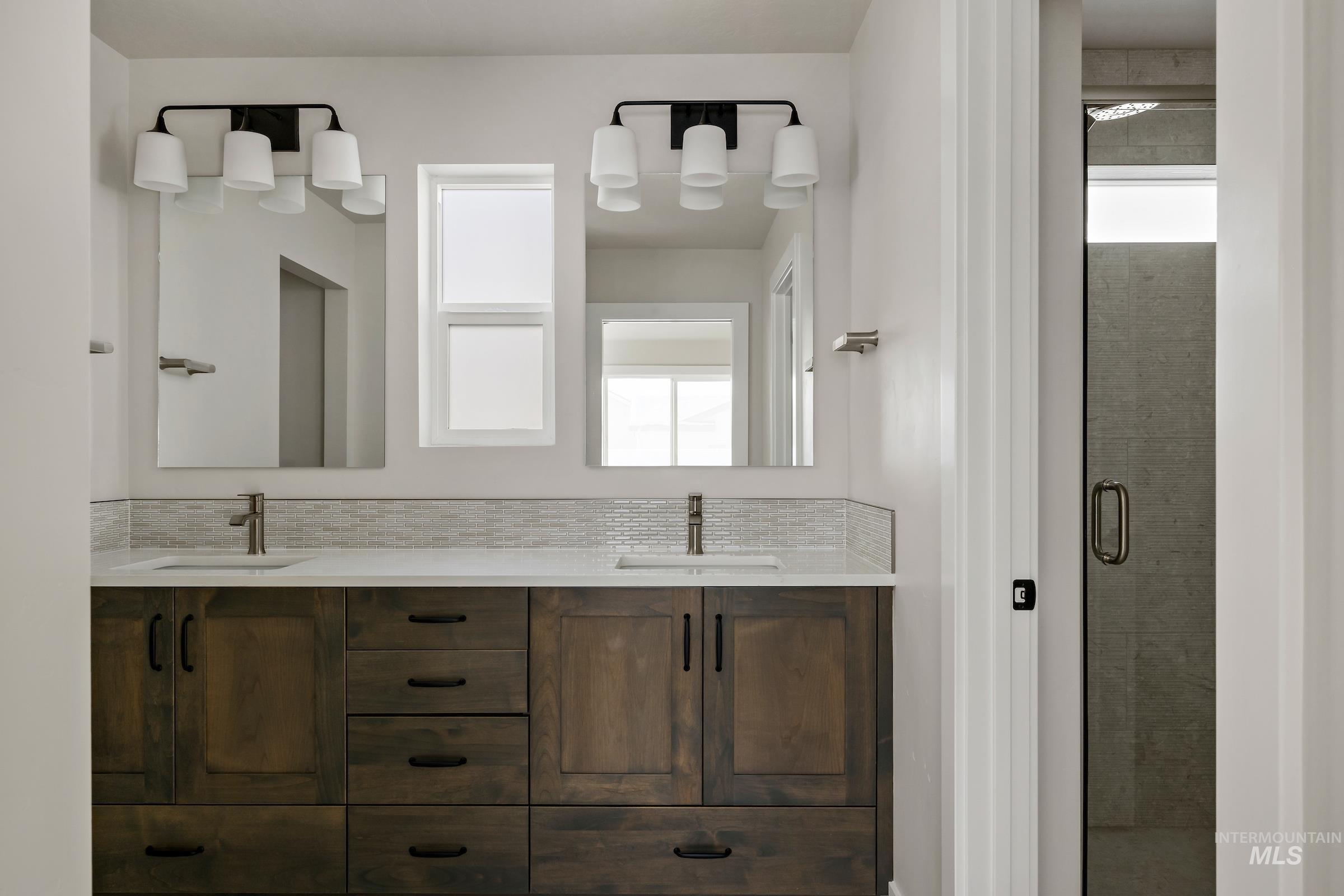 Full bathroom with double vanity, a shower stall, and decorative backsplash
