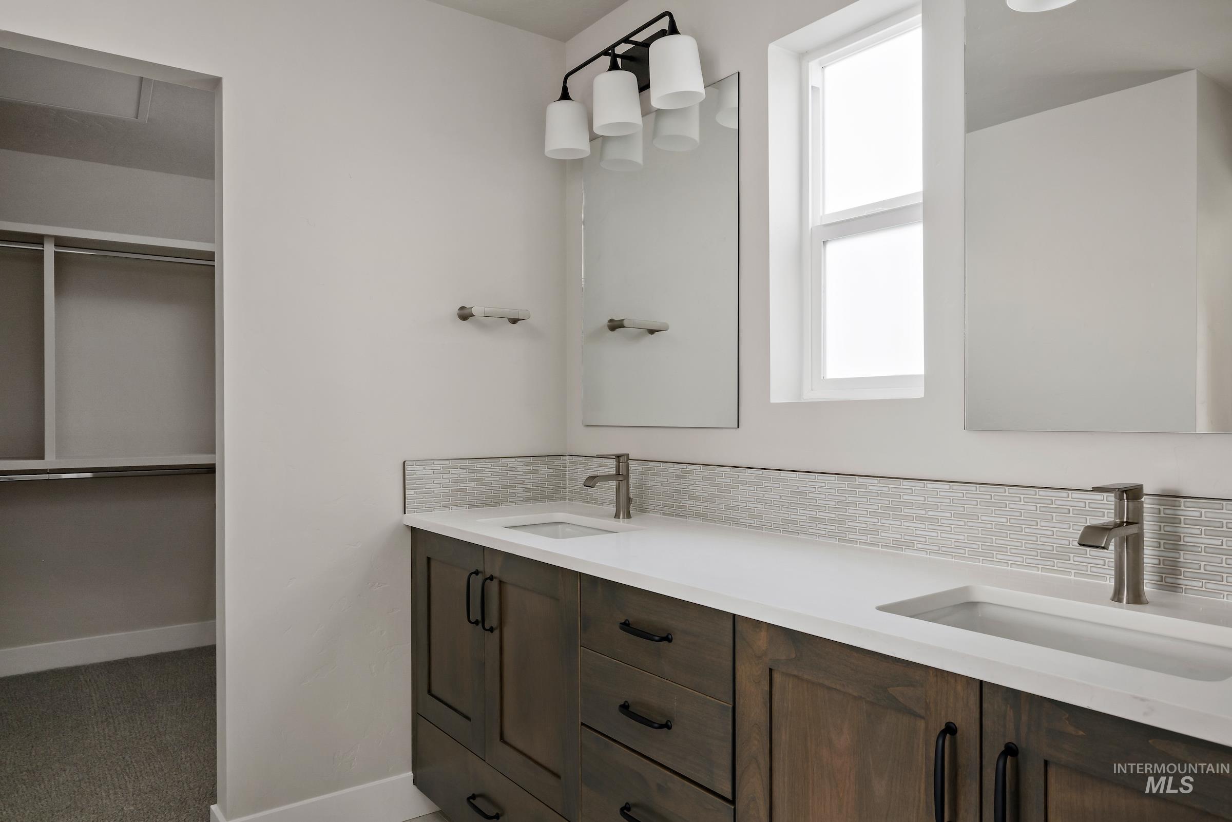 Bathroom featuring double vanity, tasteful backsplash, and a spacious closet