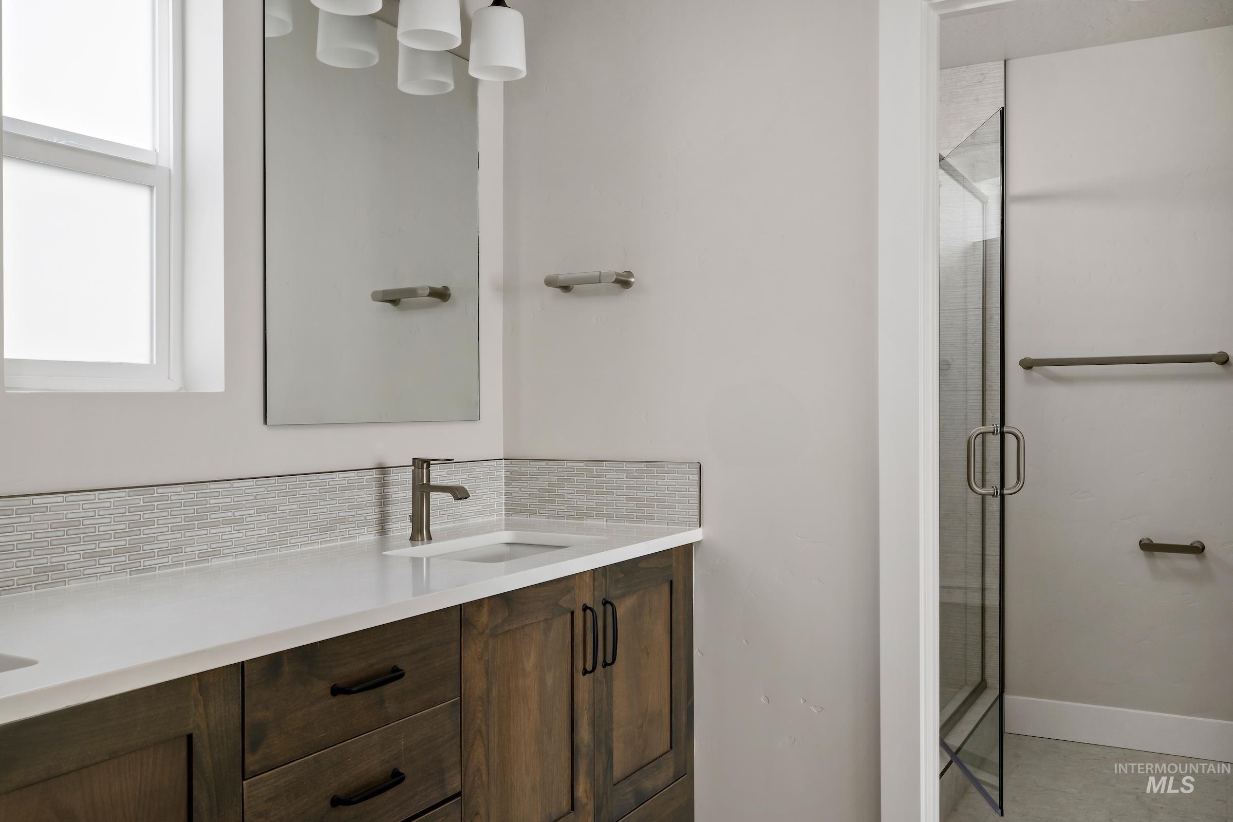 Bathroom featuring vanity, a stall shower, and decorative backsplash