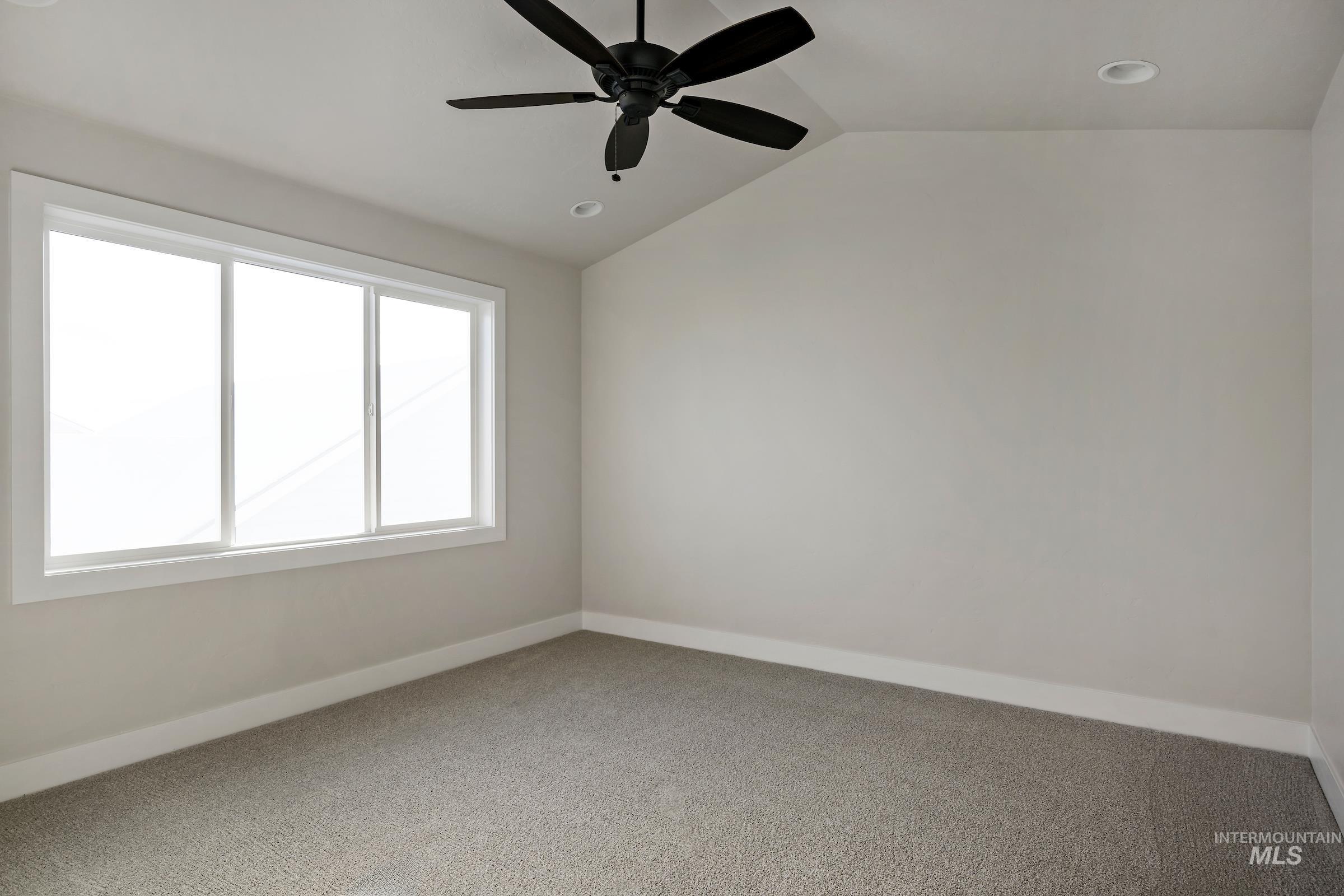 Carpeted empty room featuring vaulted ceiling, ceiling fan, and recessed lighting