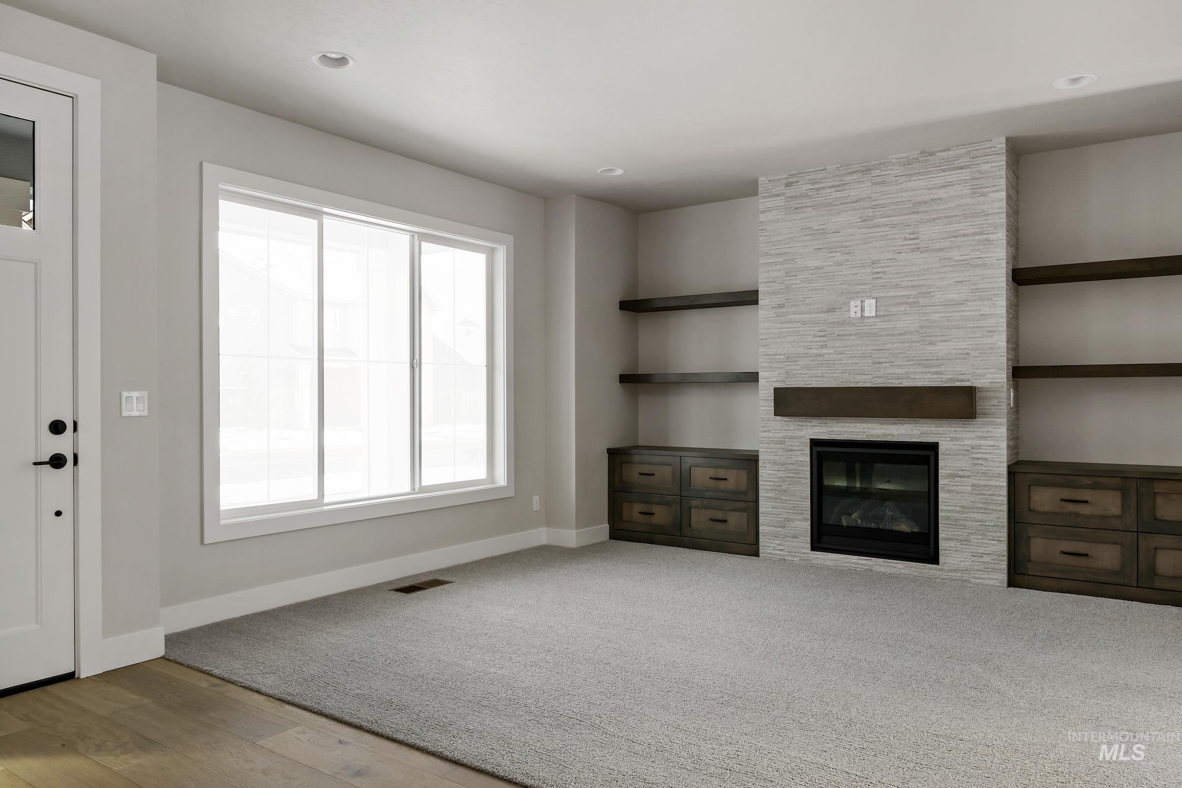 Unfurnished living room with a fireplace, light wood-style floors, and light colored carpet