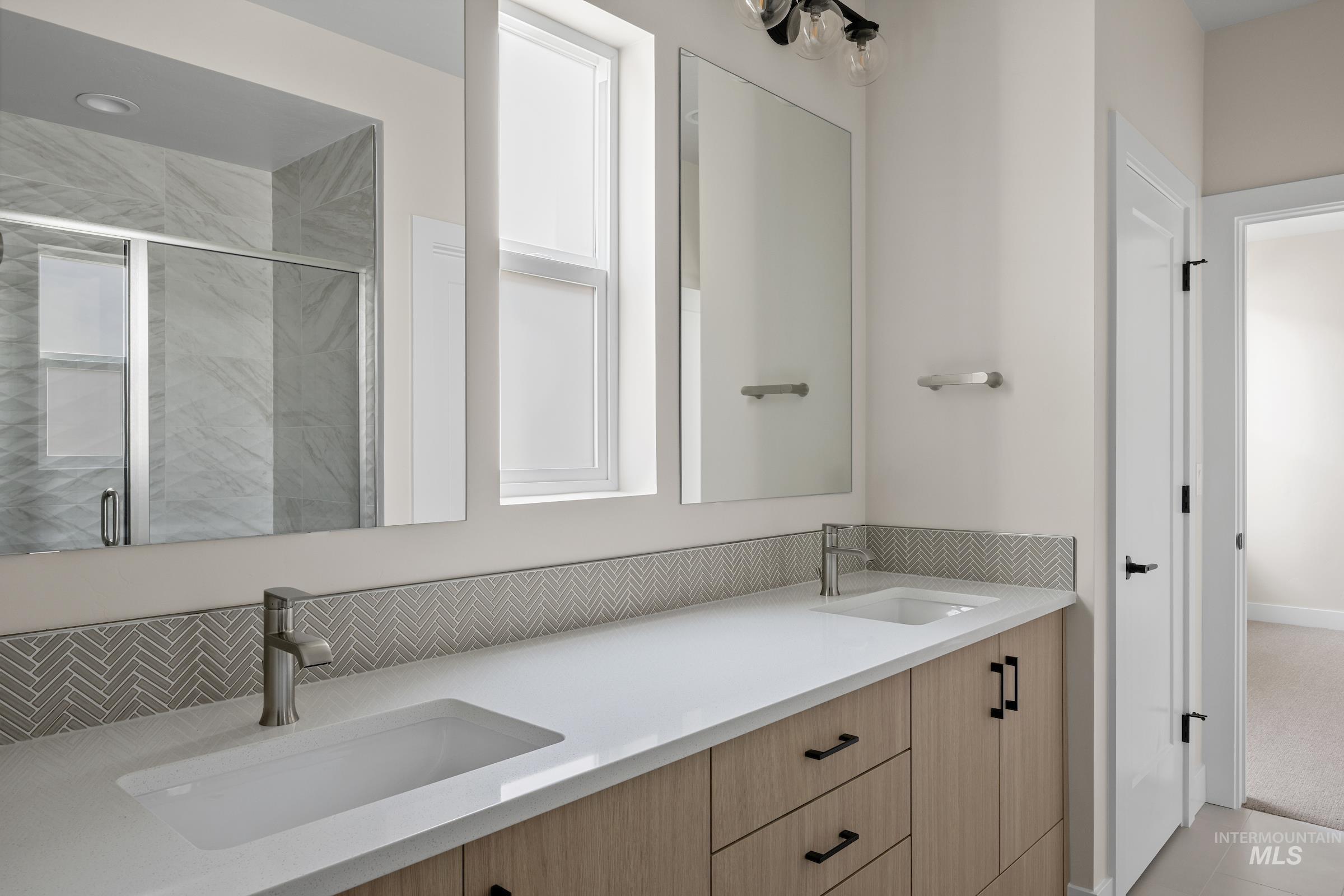 Full bath featuring double vanity and a stall shower