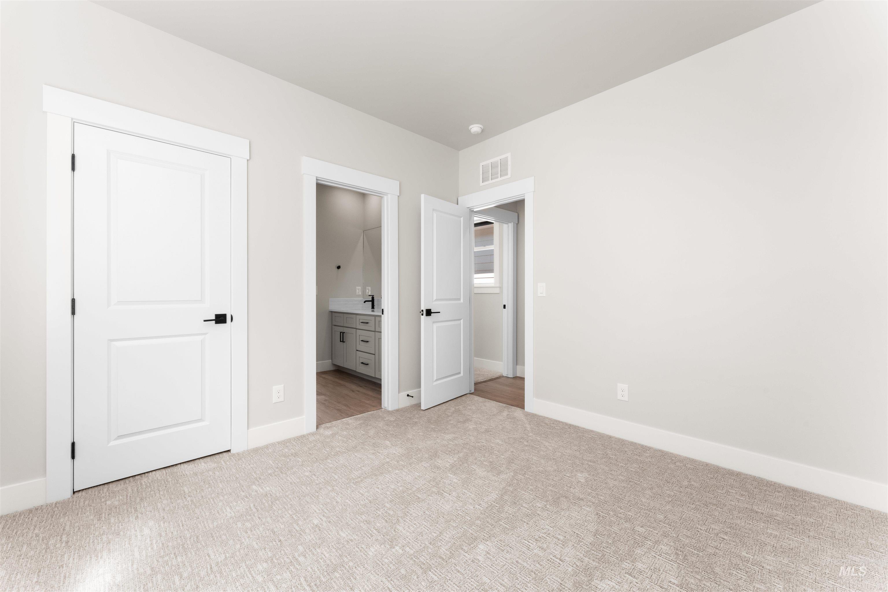 Unfurnished bedroom with carpet flooring and ensuite bathroom