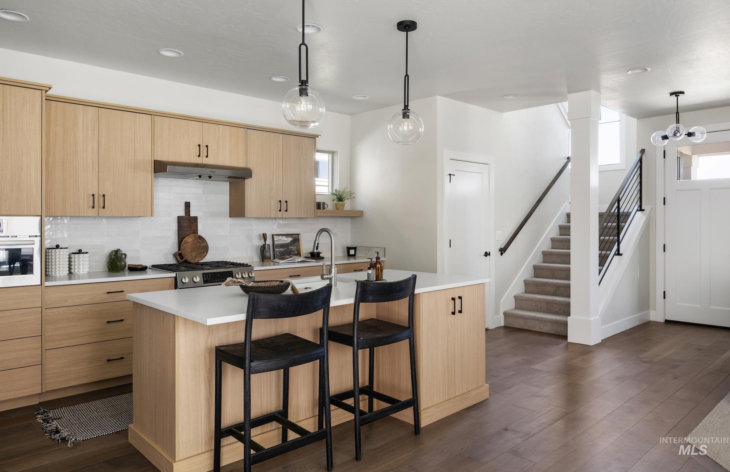 Kitchen featuring light countertops, a kitchen bar, dark wood finished floors, appliances with stainless steel finishes, and recessed lighting