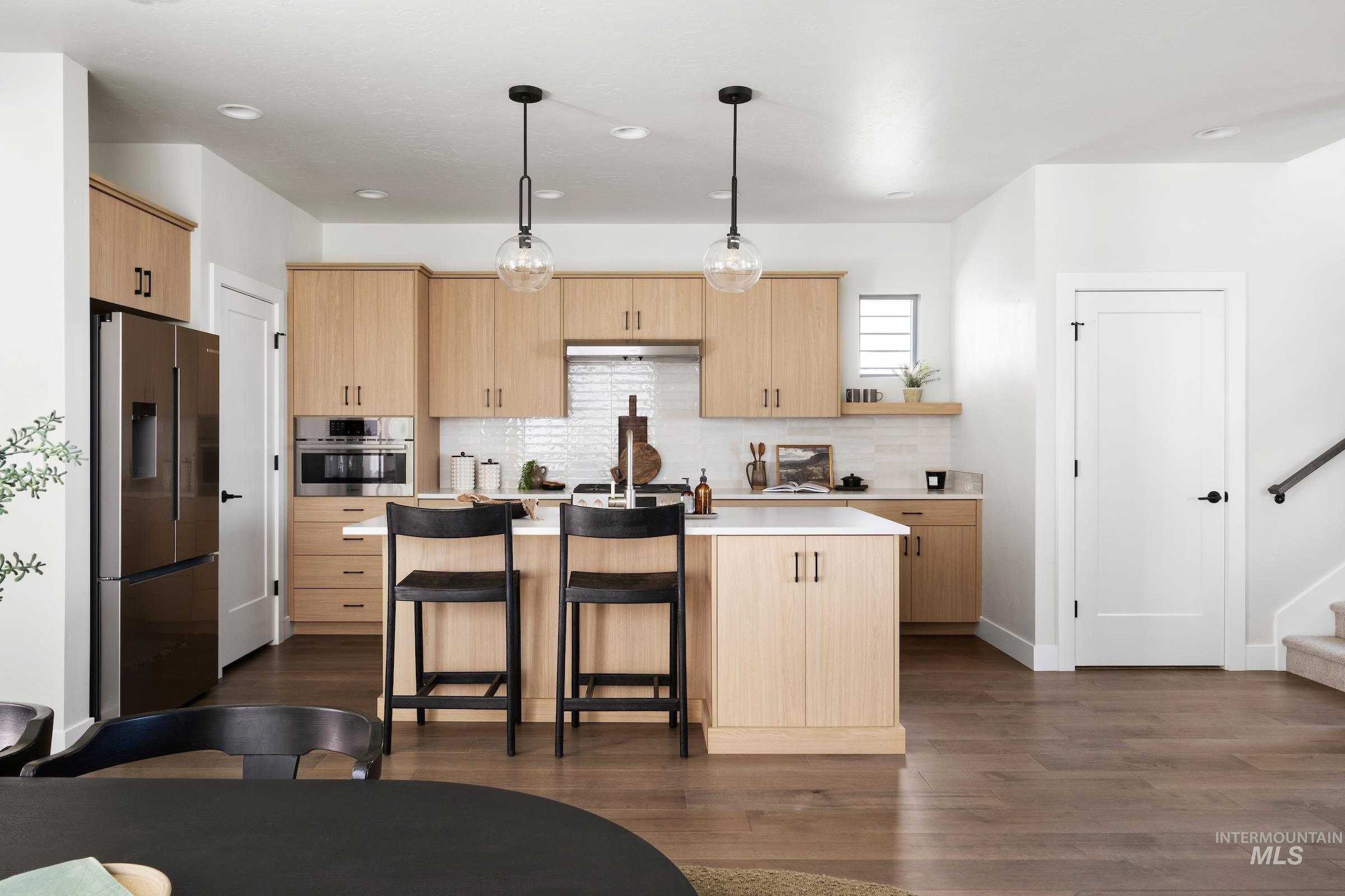 Kitchen featuring light brown cabinetry, decorative light fixtures, tasteful backsplash, appliances with stainless steel finishes, and recessed lighting