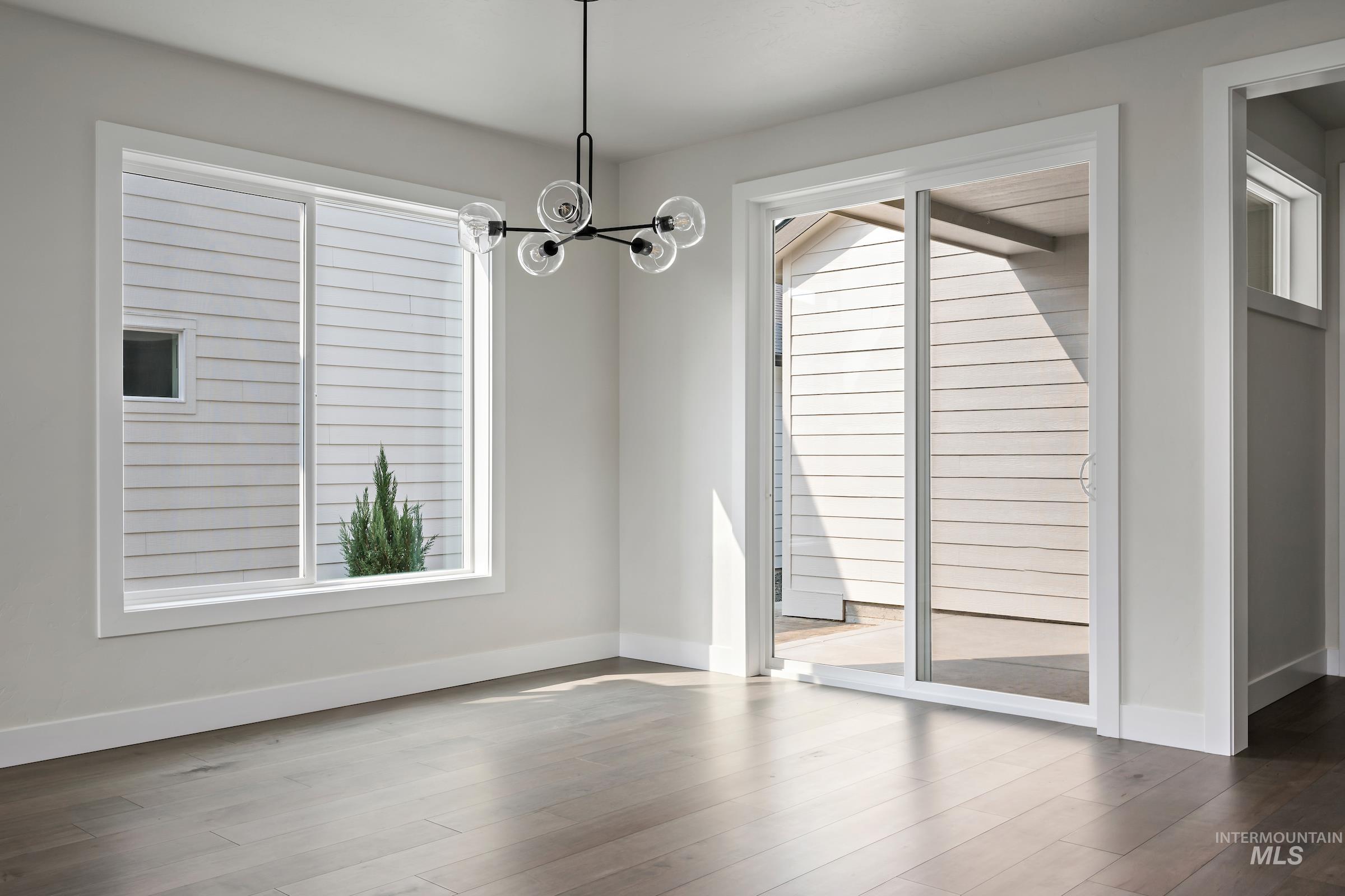 Unfurnished dining area featuring wood finished floors and a chandelier