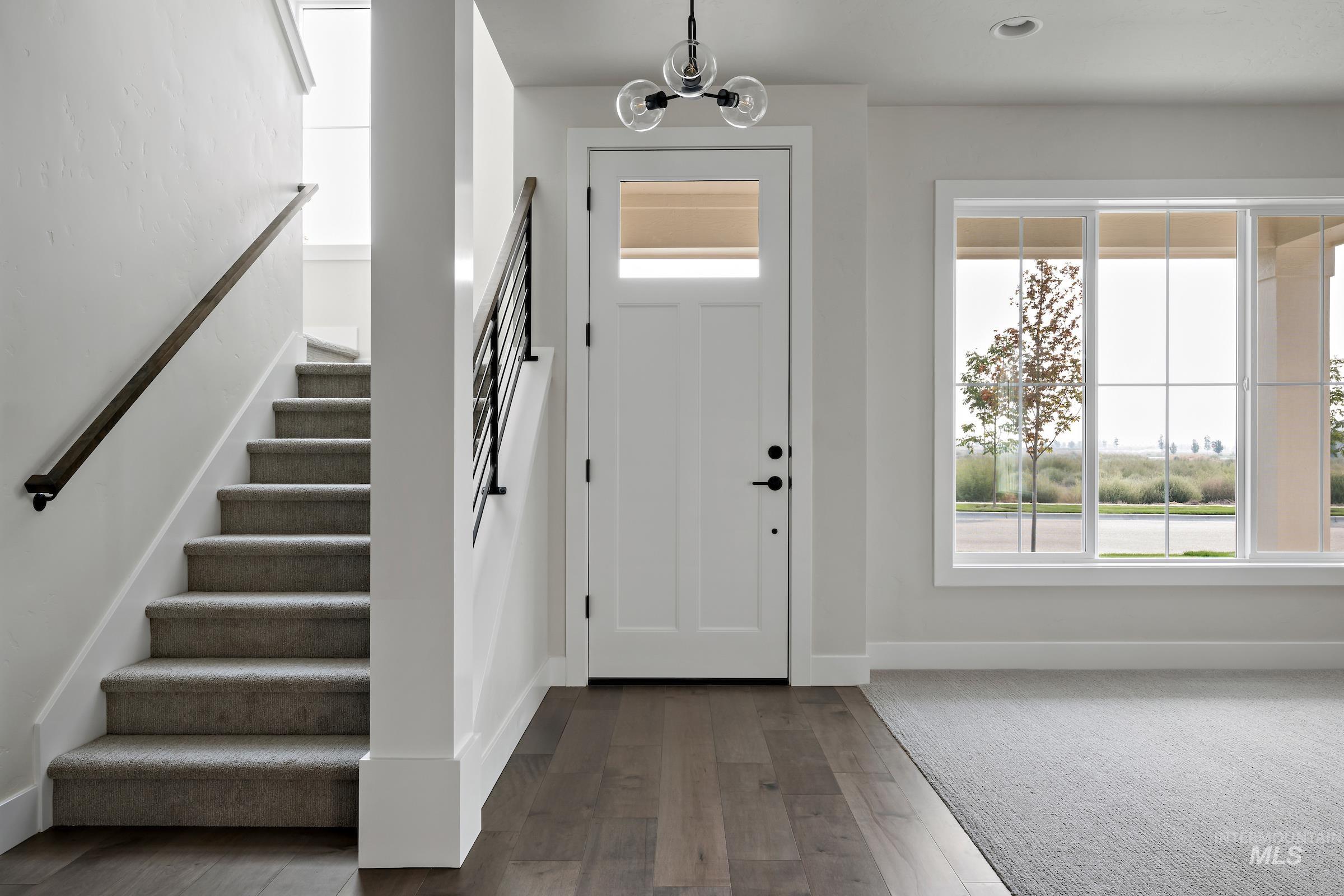Entrance foyer with stairway, dark wood-style floors, and a chandelier
