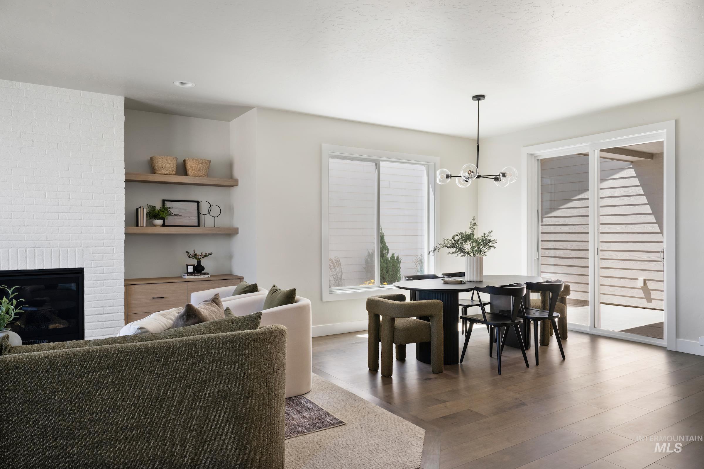 Dining area with wood finished floors, a brick fireplace, and a chandelier