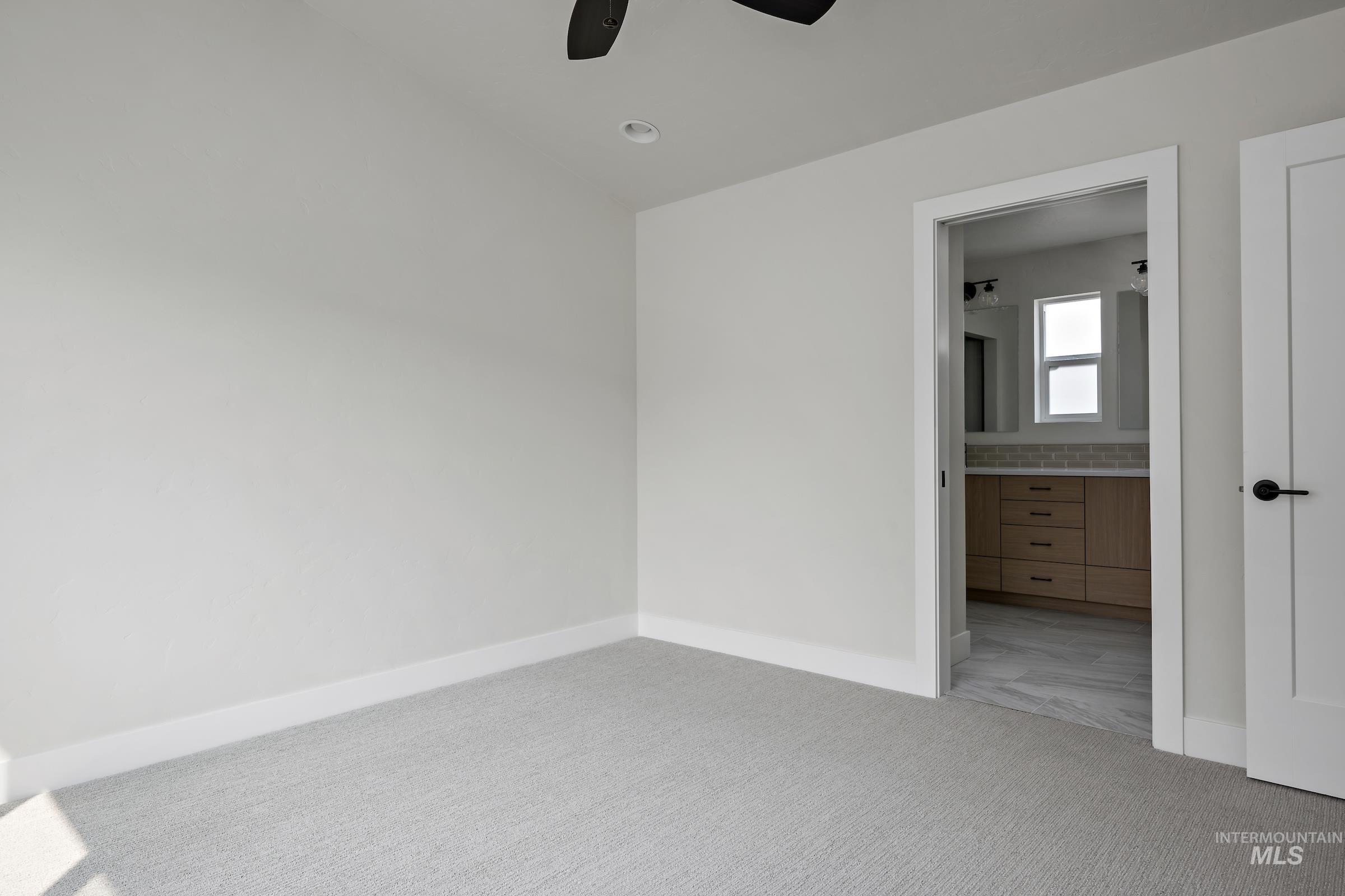 Unfurnished bedroom with carpet flooring, connected bathroom, and a ceiling fan