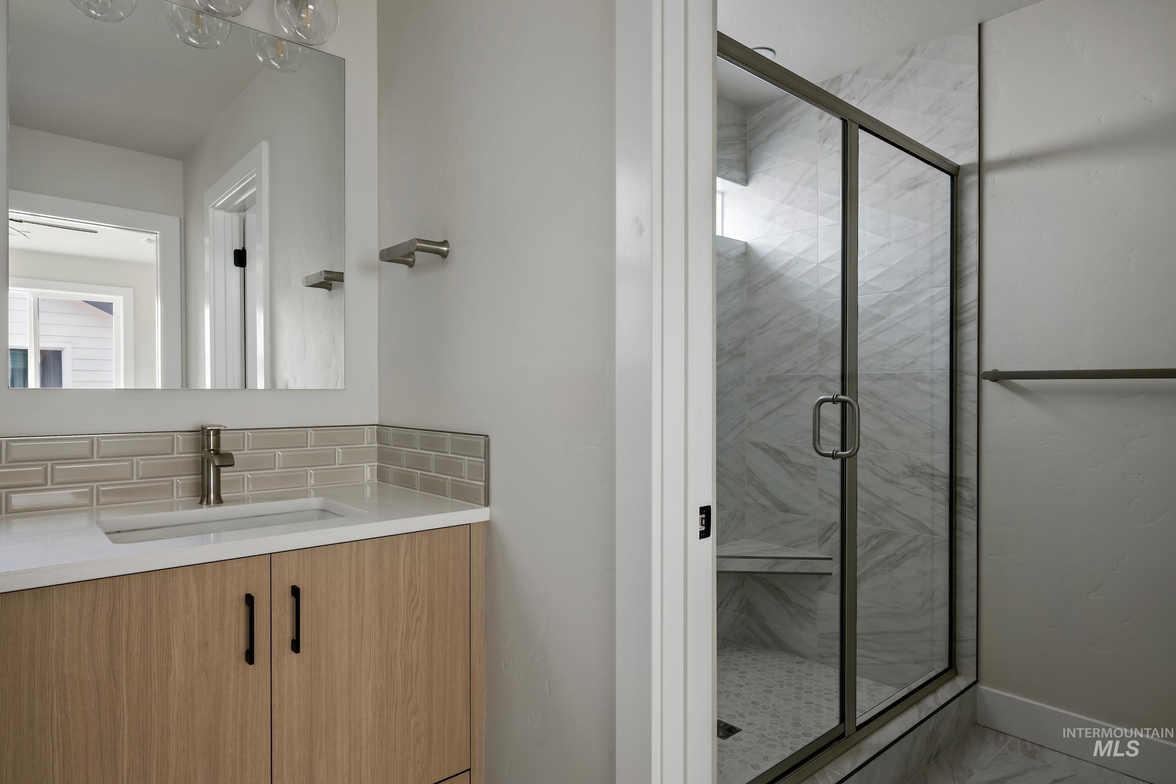 Full bath featuring vanity and a marble finish shower
