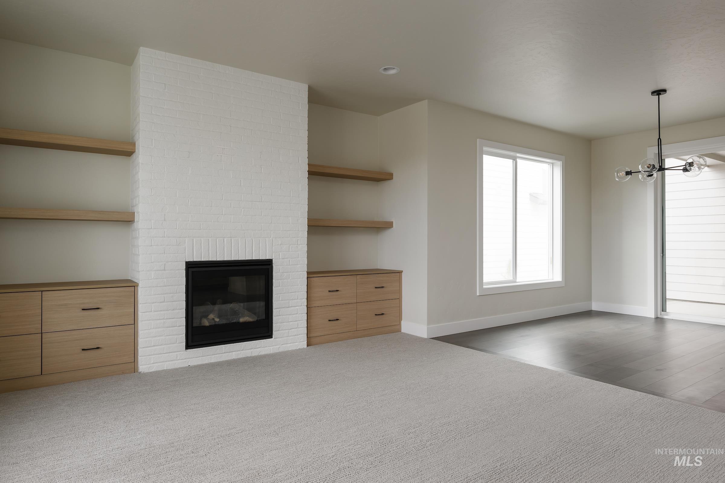 Unfurnished living room with a fireplace, a chandelier, and carpet flooring