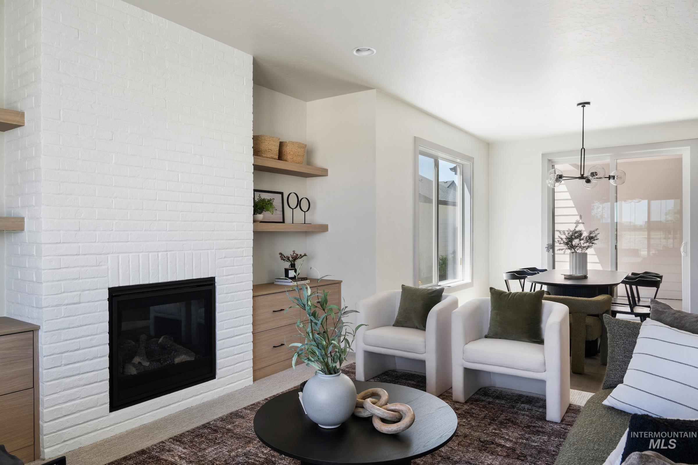 Living area with a chandelier, a fireplace, and dark carpet