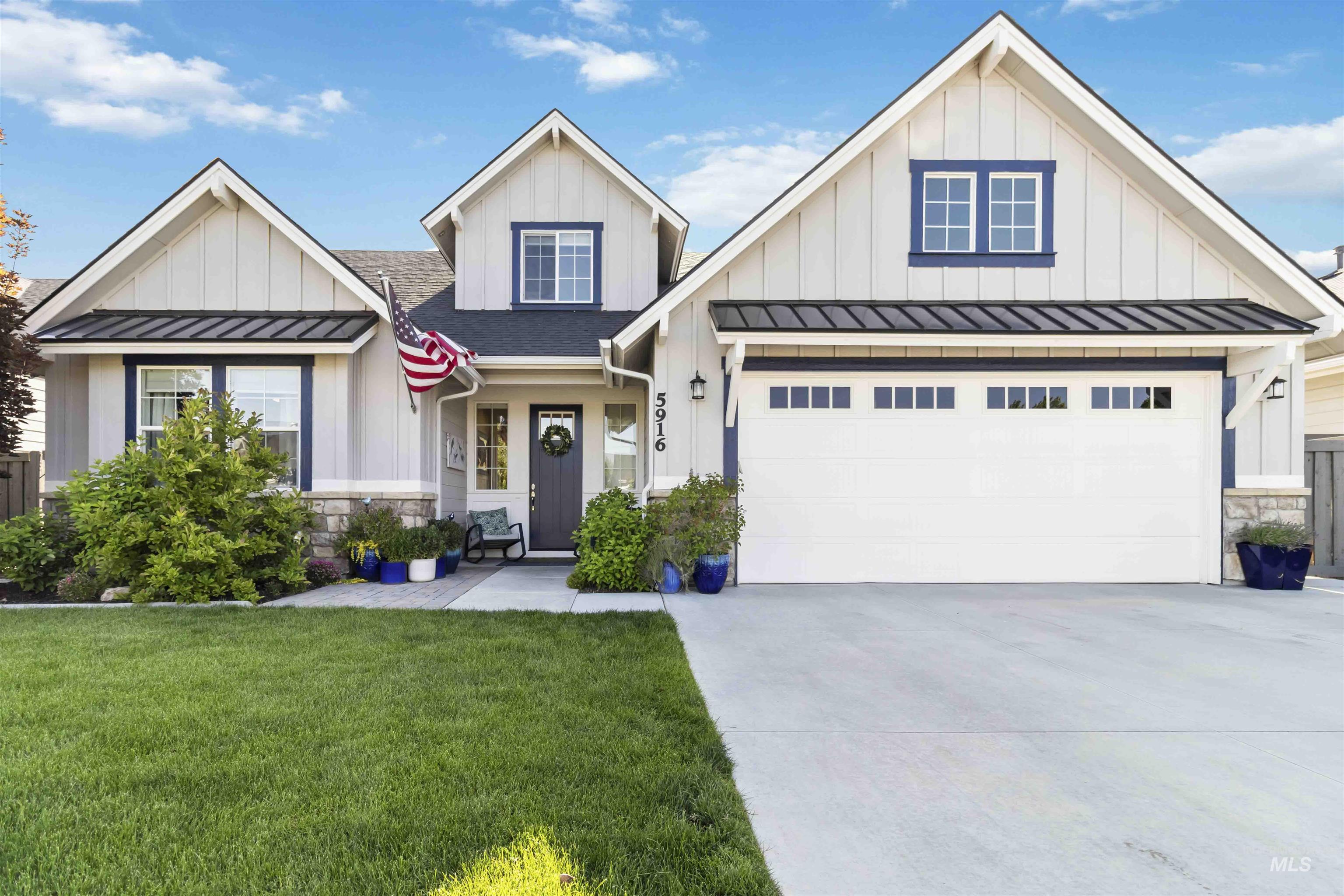 Modern farmhouse featuring a standing seam roof, stone siding, board and batten siding, and a metal roof
