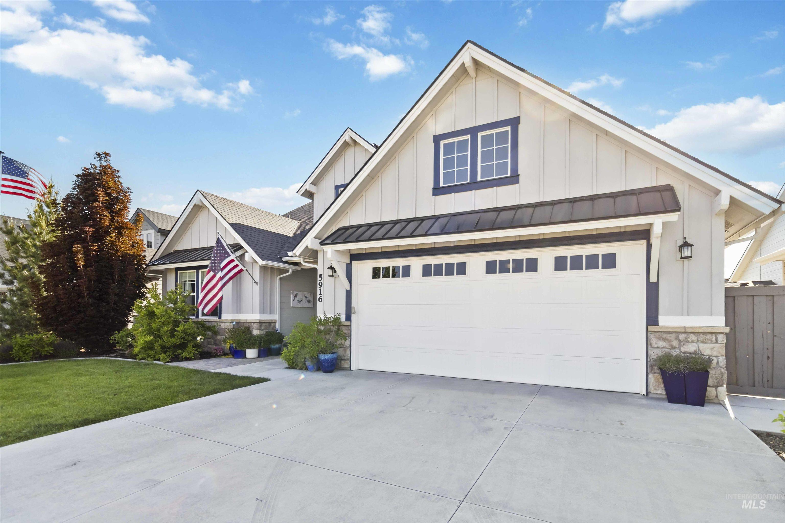Modern inspired farmhouse with board and batten siding, stone siding, a standing seam roof, a garage, and a metal roof
