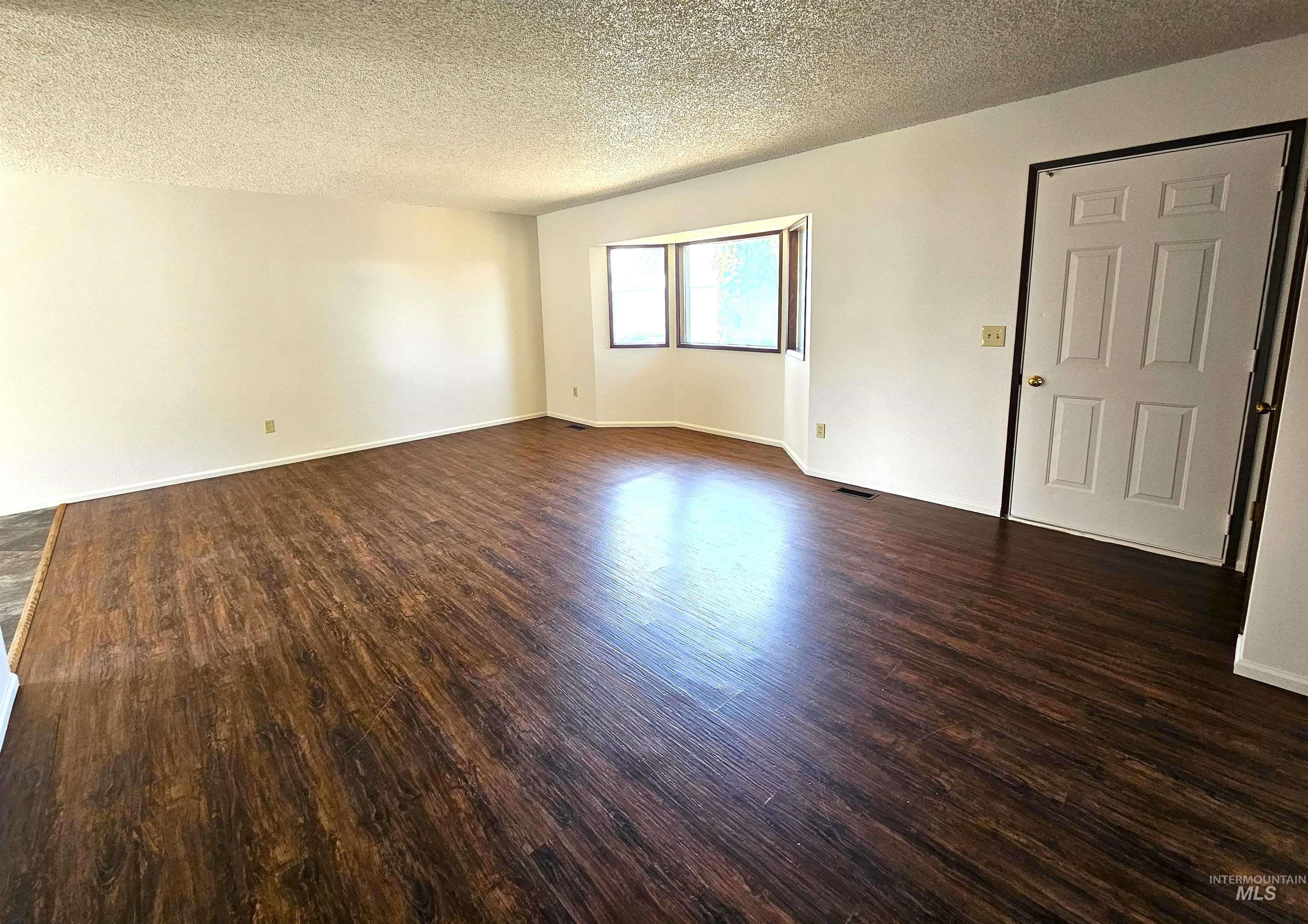 Spare room with a textured ceiling and dark wood-style floors