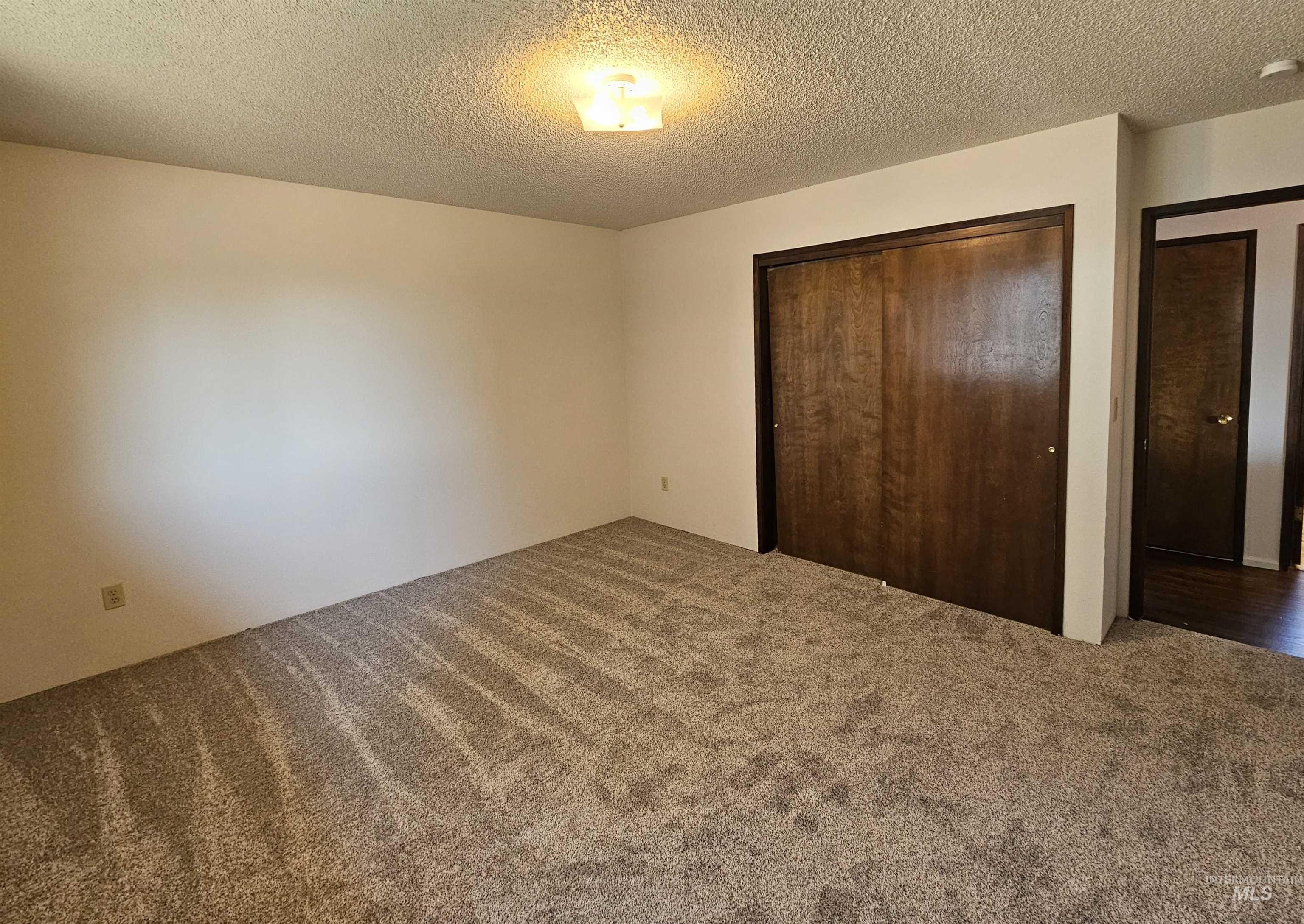 Unfurnished bedroom with a textured ceiling, carpet, and a closet