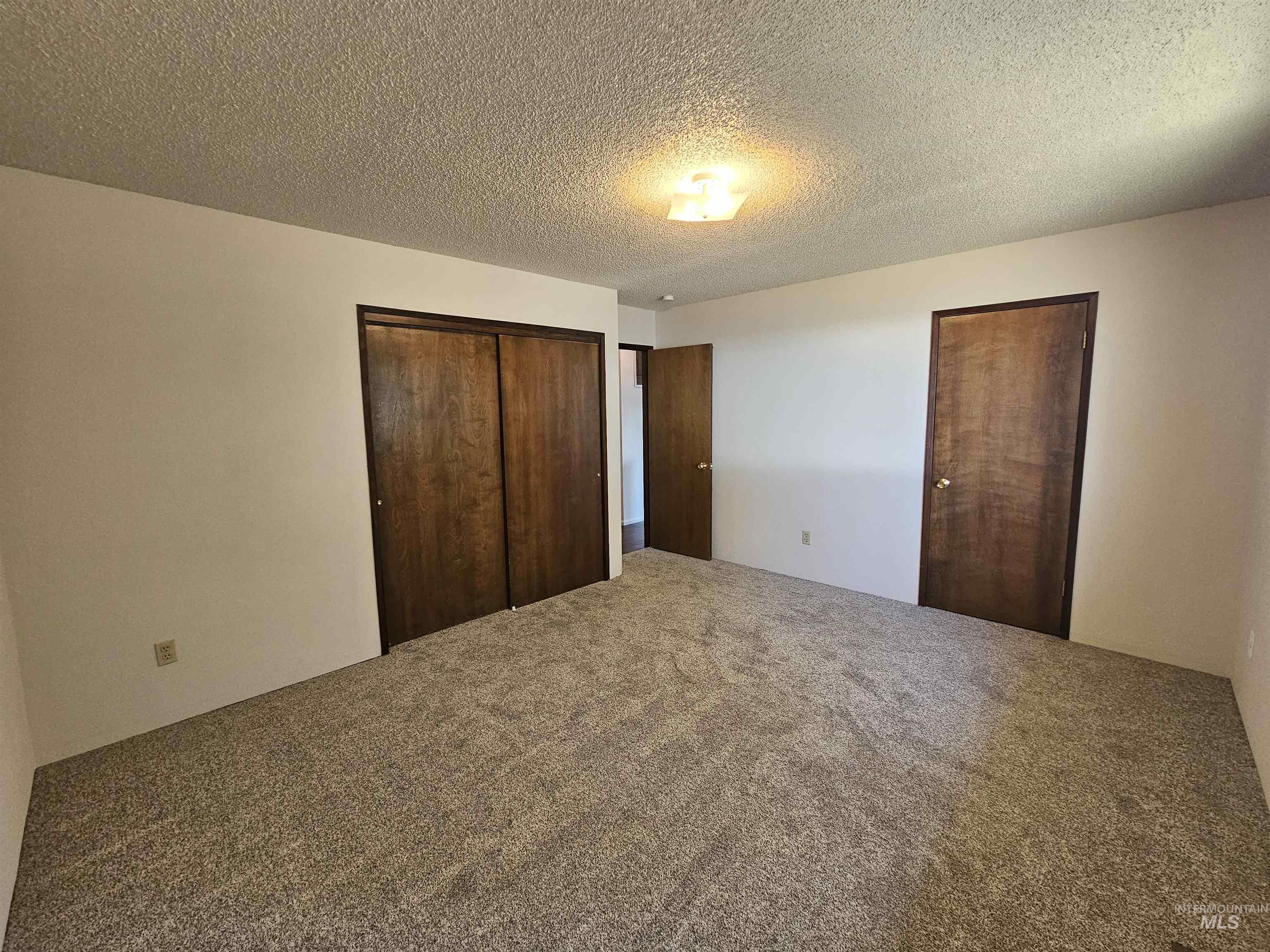 Unfurnished bedroom with a closet, a textured ceiling, and carpet floors
