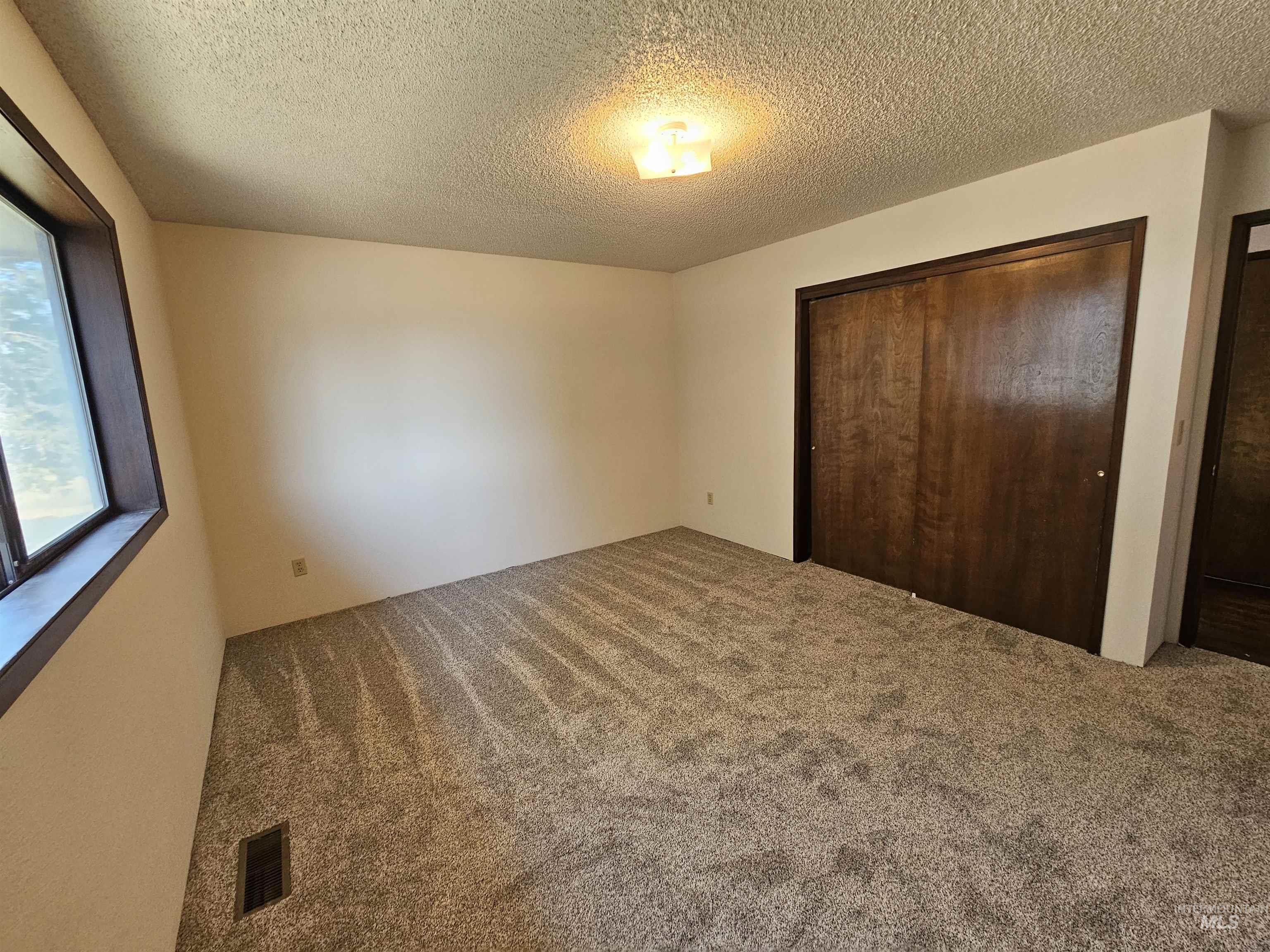 Unfurnished bedroom with carpet, a textured ceiling, and a closet