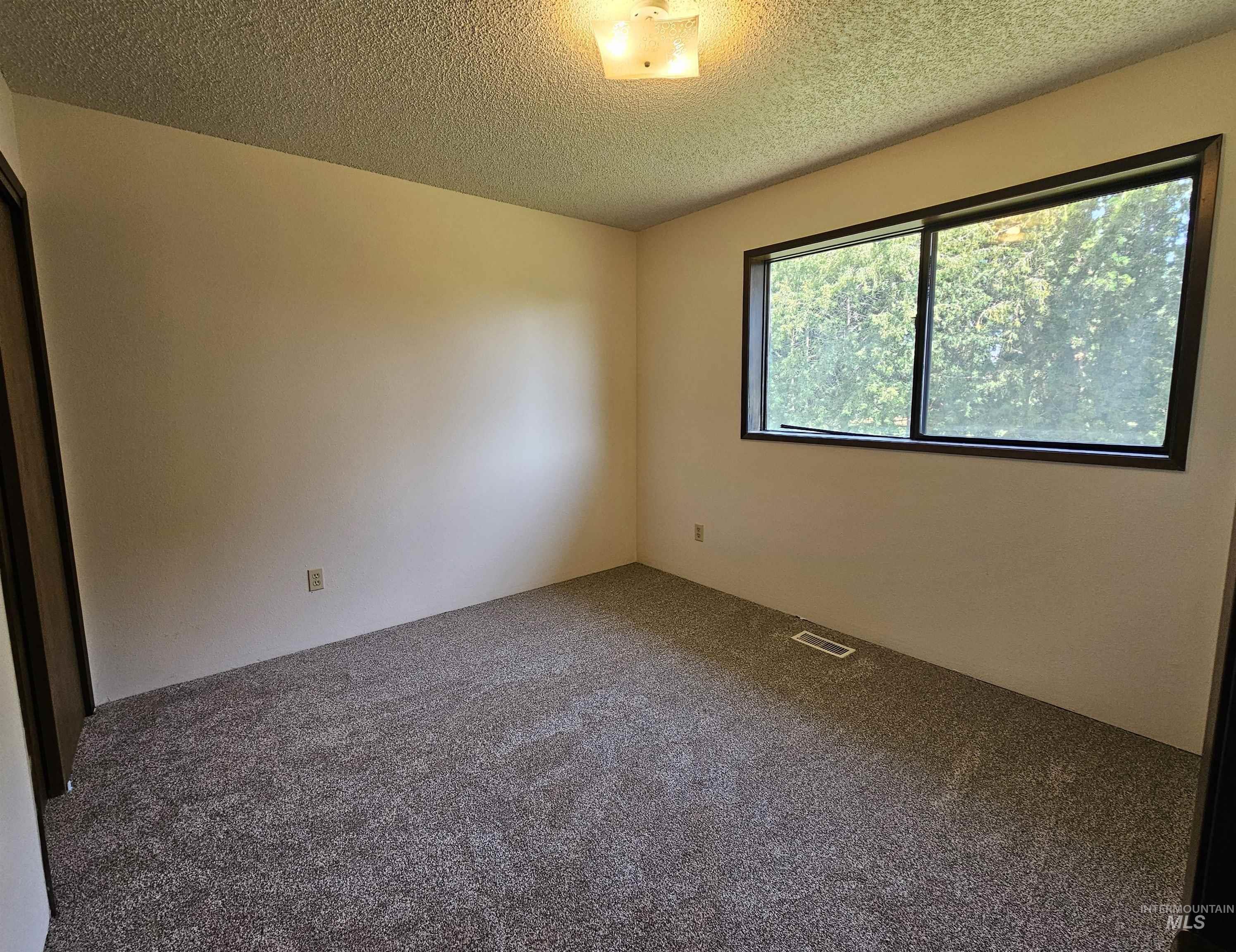 Spare room featuring carpet and a textured ceiling