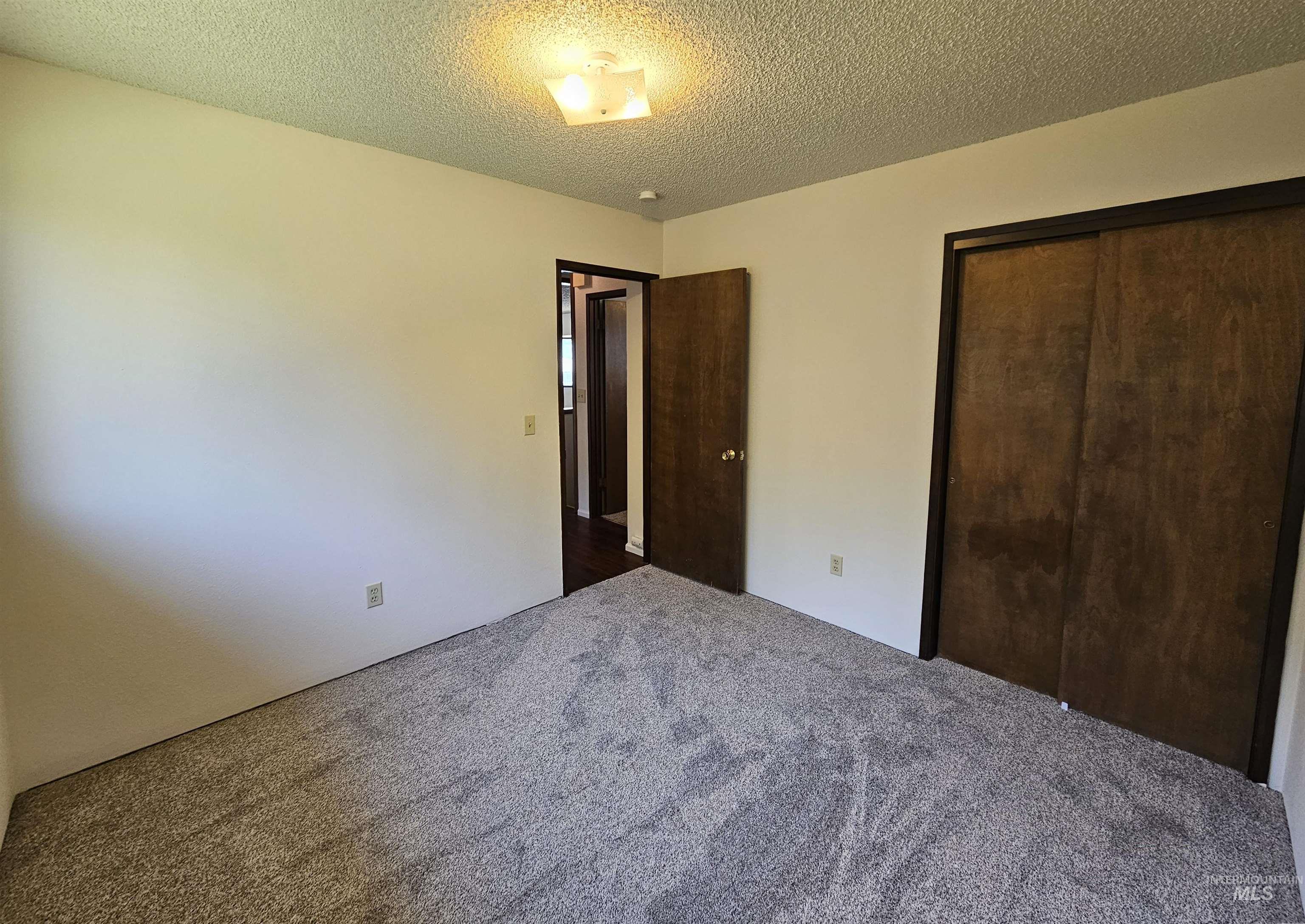 Unfurnished bedroom with a textured ceiling, a closet, and carpet flooring