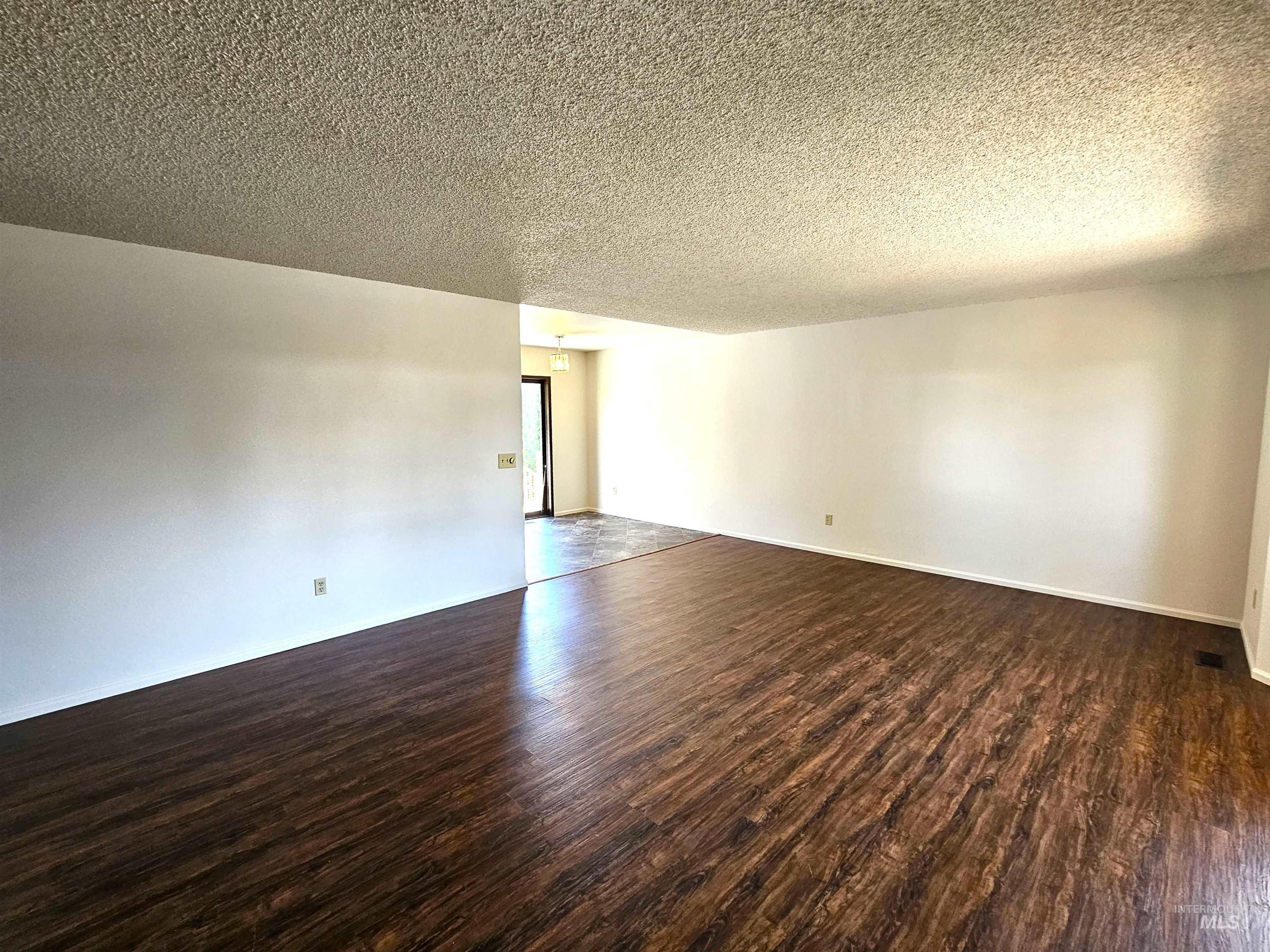 Unfurnished room with dark wood-style floors and a textured ceiling