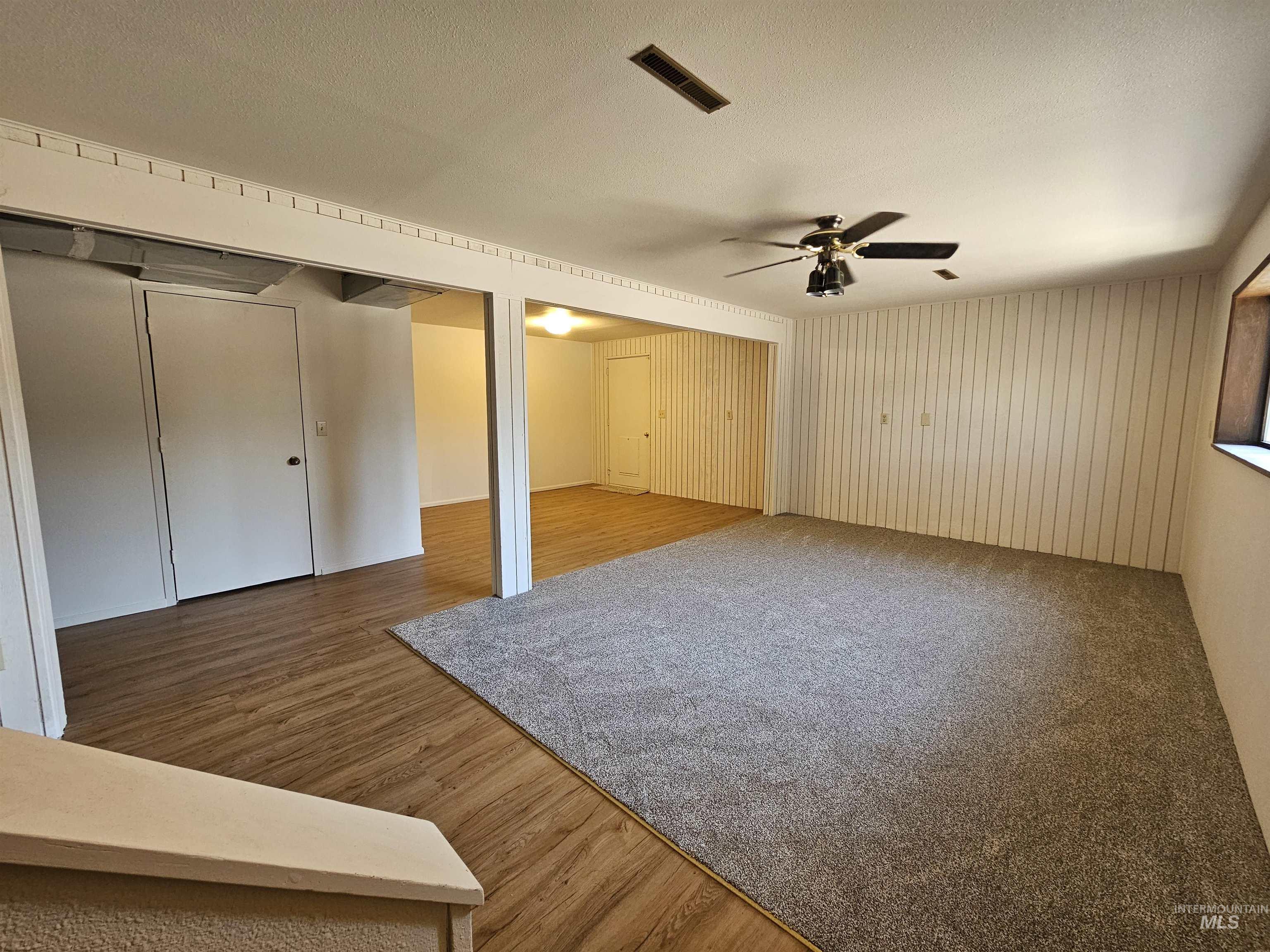 Unfurnished bedroom with light wood-style flooring, two closets, a ceiling fan, and a textured ceiling