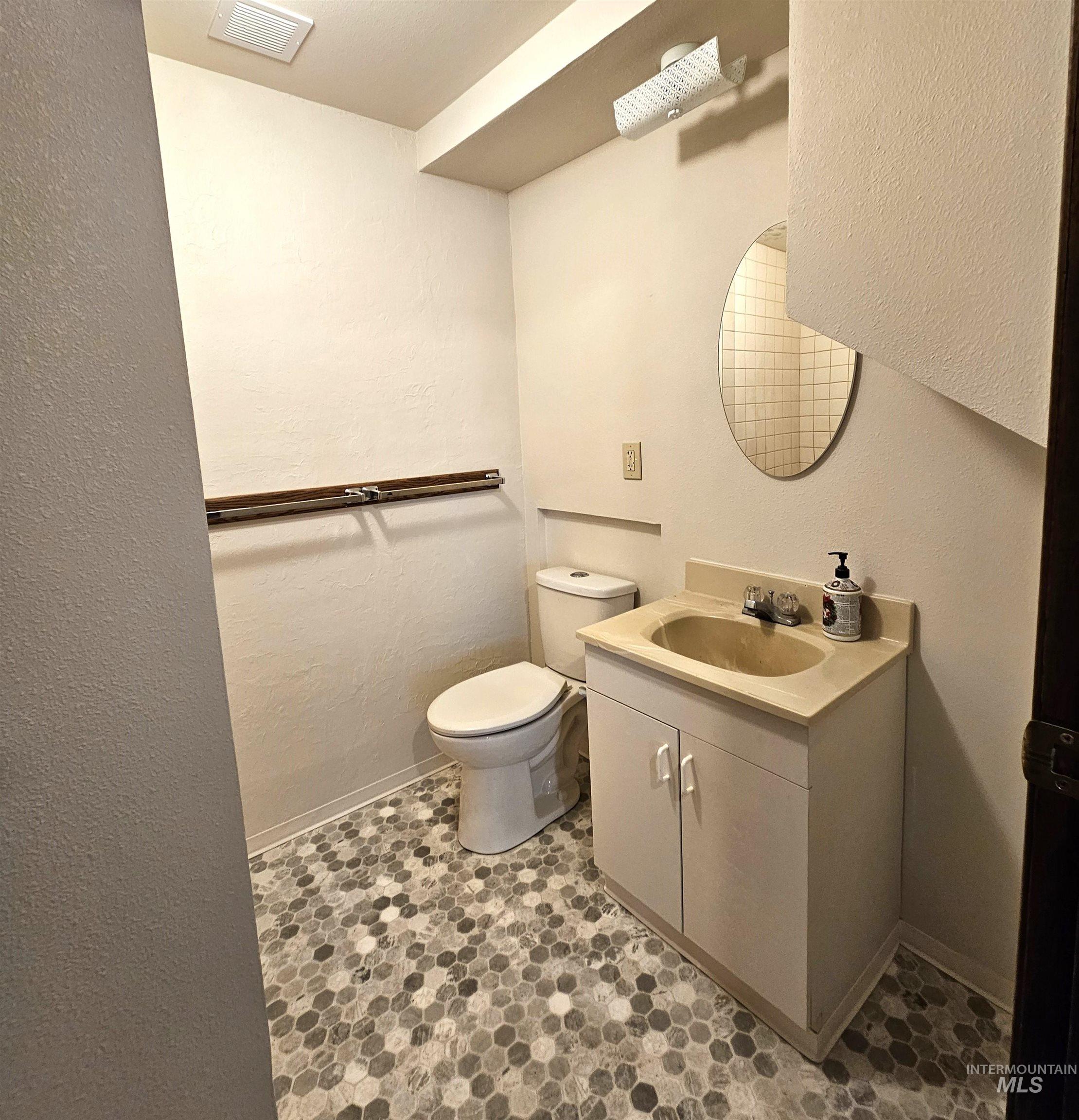 Half bathroom featuring a textured wall and vanity