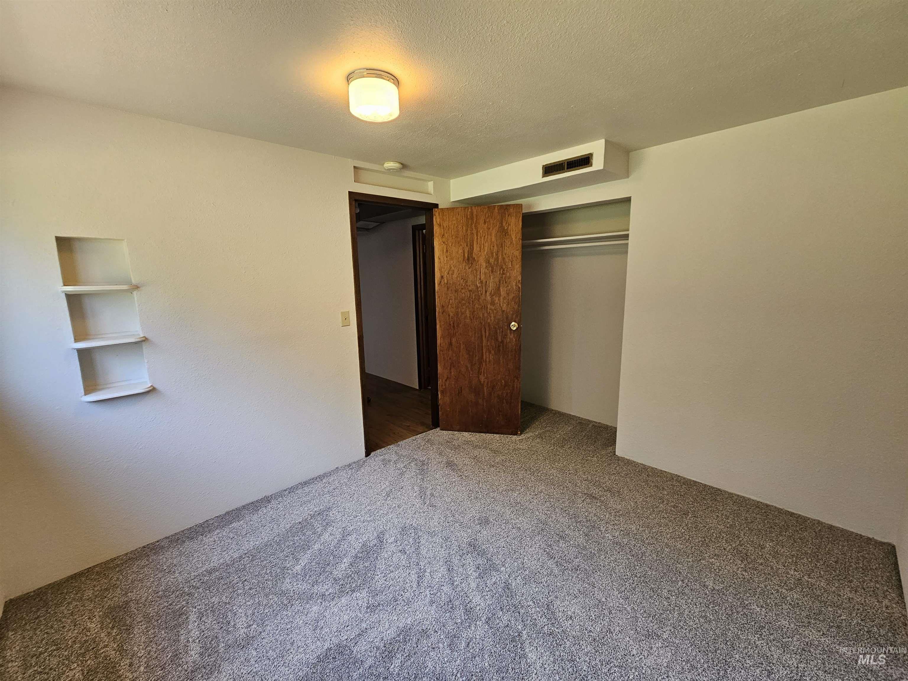 Unfurnished bedroom featuring a textured ceiling, a closet, and carpet flooring