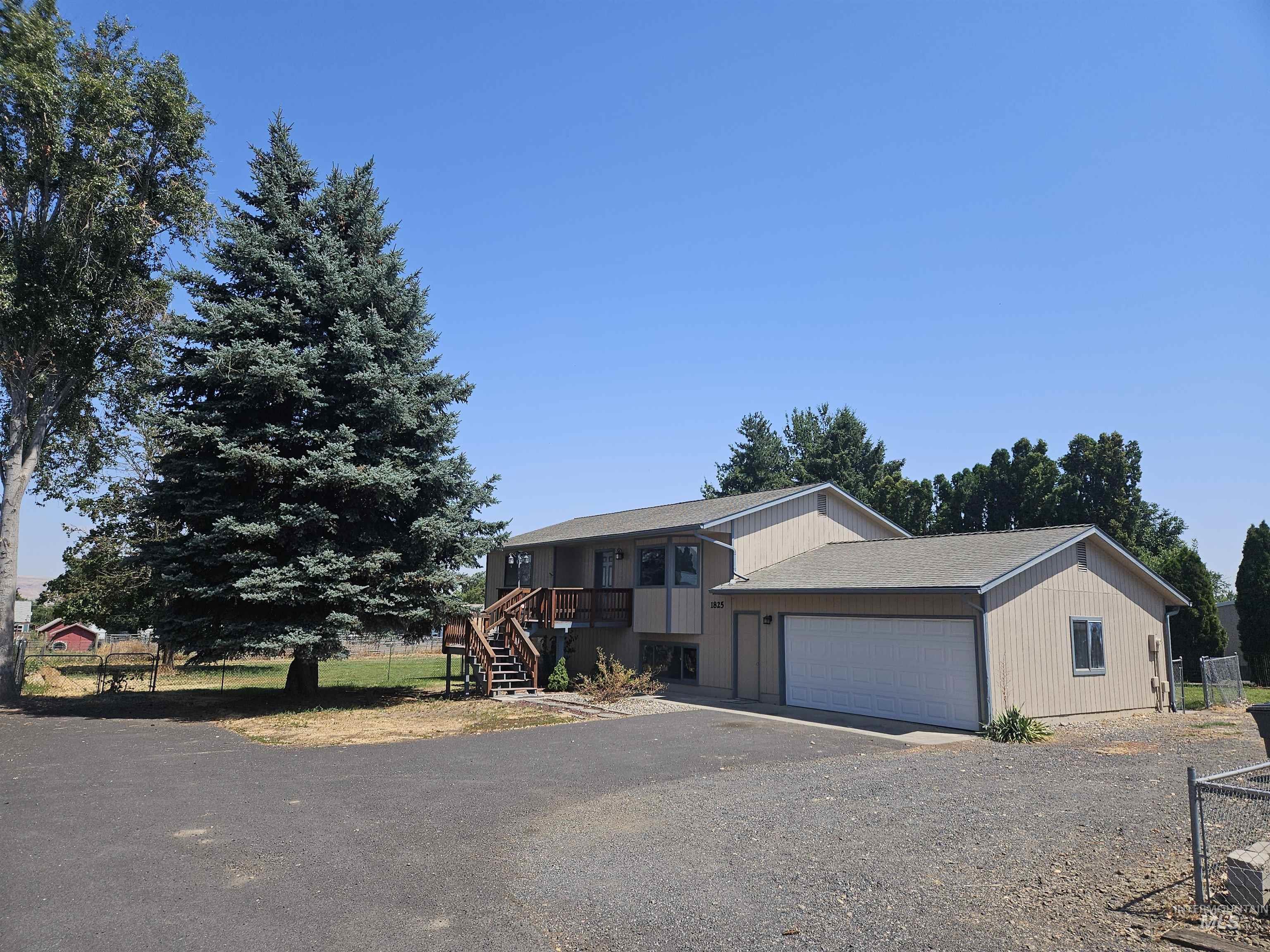 View of front facade with asphalt driveway, a garage, a shingled roof, and stairway