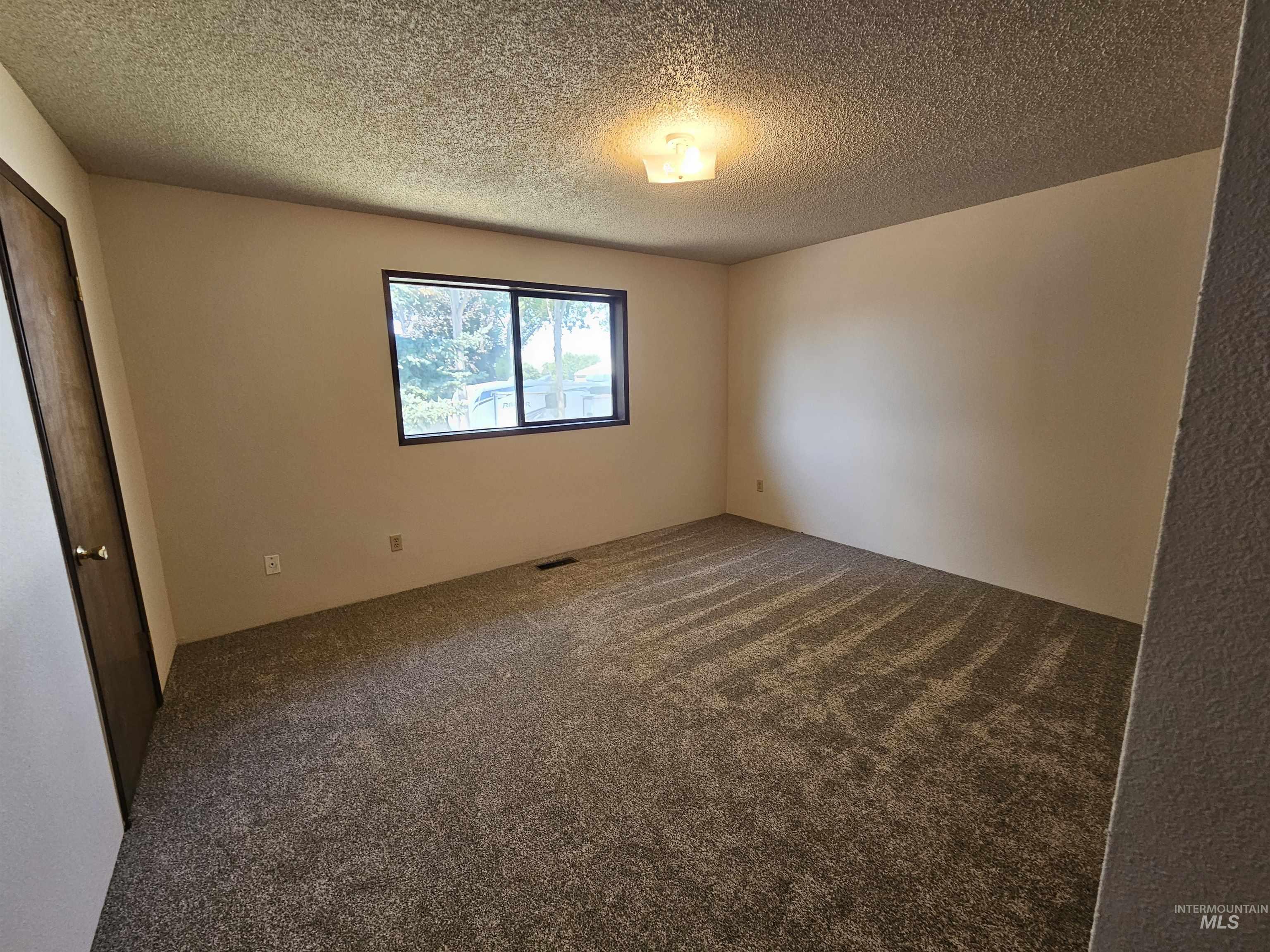 Unfurnished room featuring dark carpet and a textured ceiling